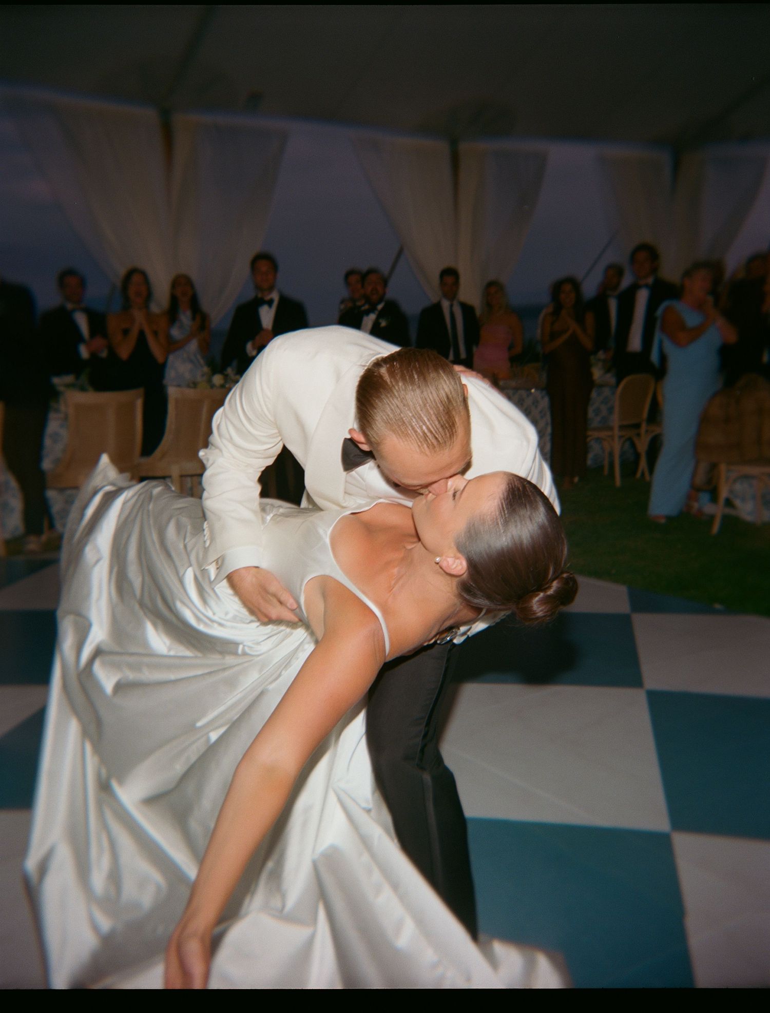 Romantic dip dance on checkered floor during wedding reception.