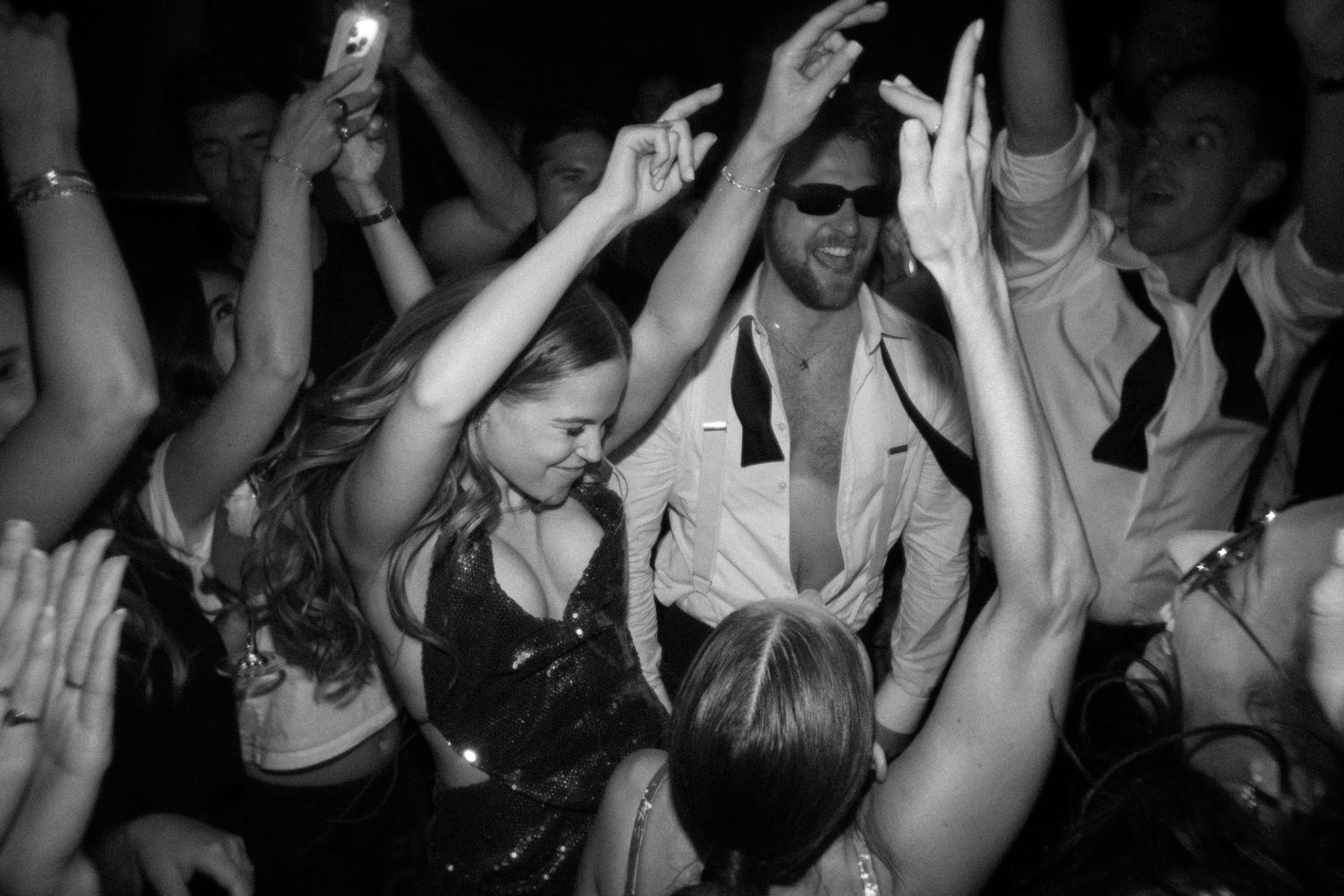Crowd of party guests with raised hands dancing at a celebration.