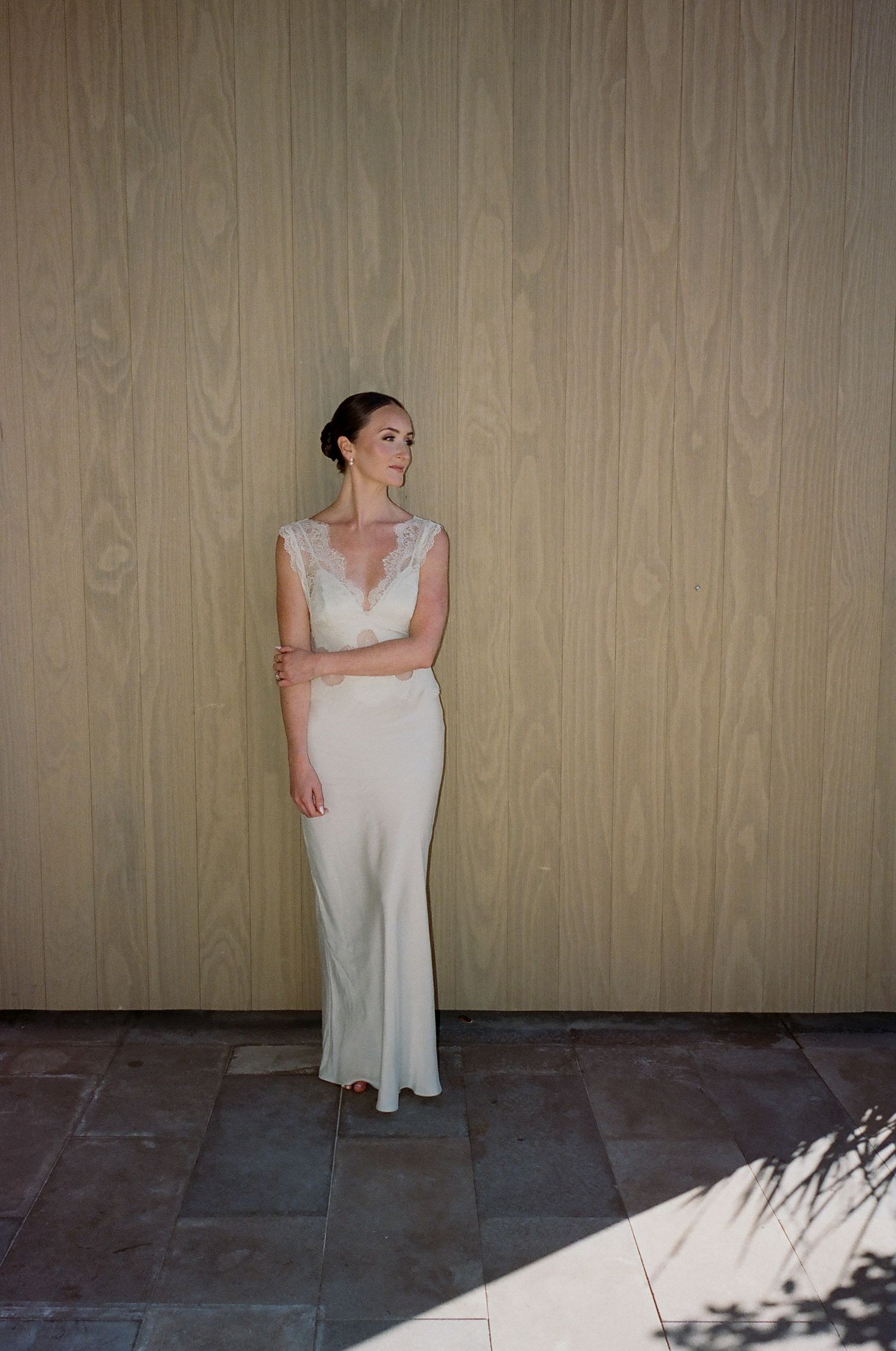 Elegant bridal portrait against wooden wall with natural lighting.