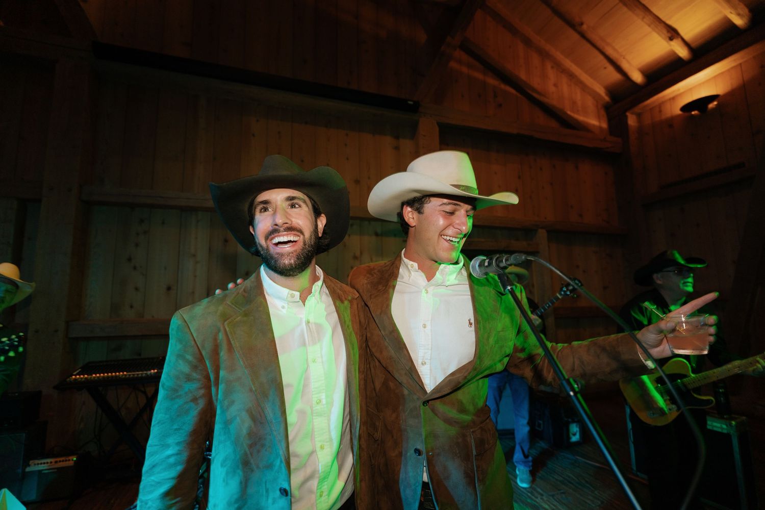 Two performers in cowboy hats on stage with colorful lighting.
