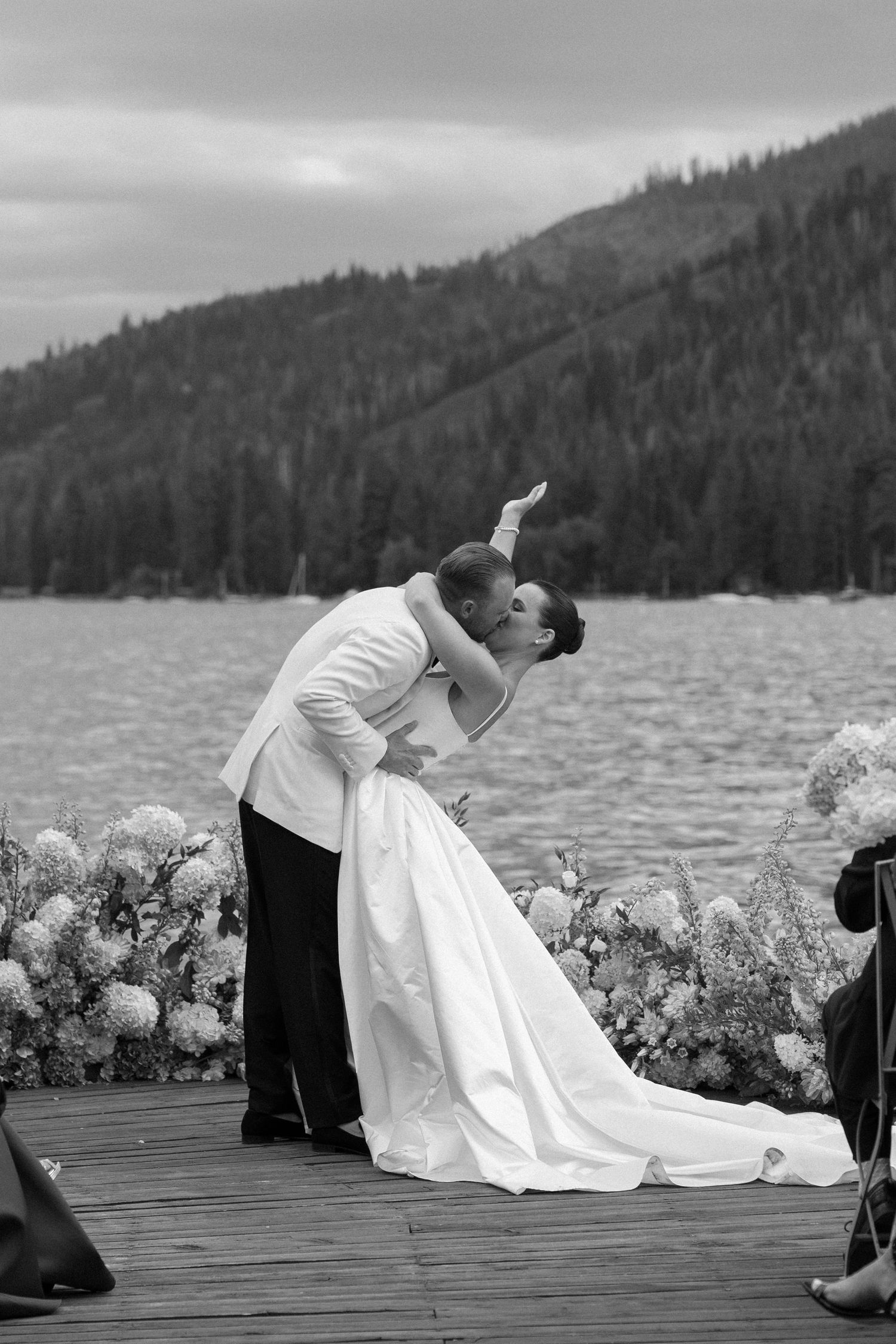 Romantic wedding portrait of couple in dramatic dip pose on lakeside dock.