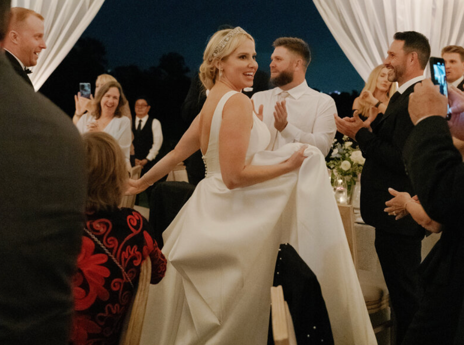 Wedding reception dance floor filled with guests celebrating in warm lighting.