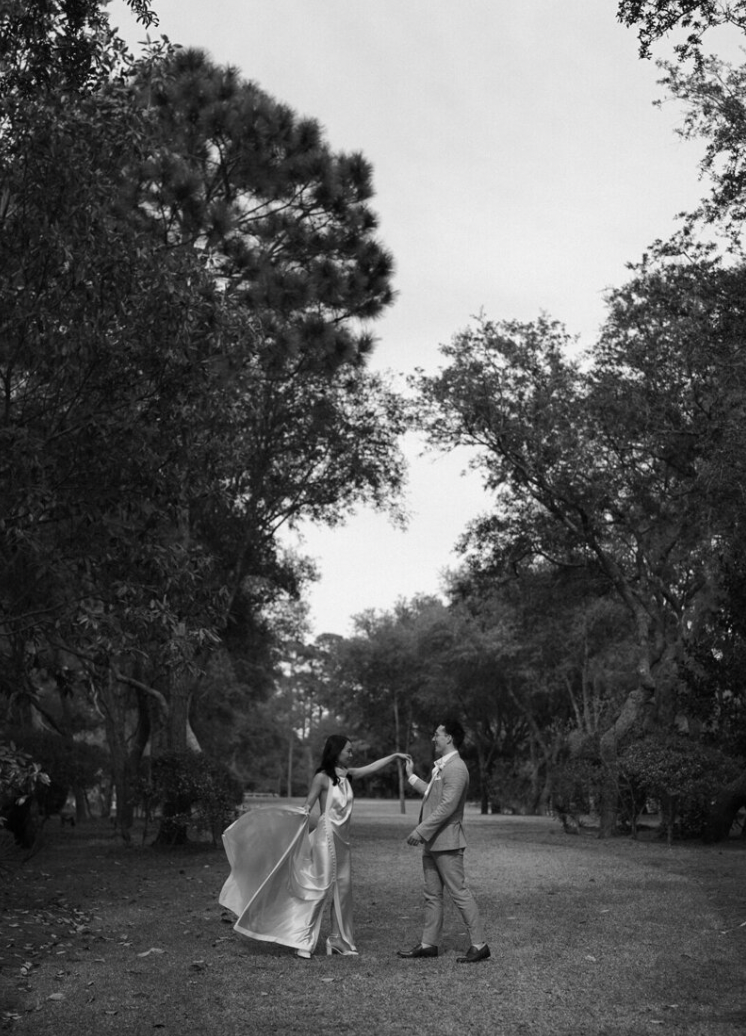 Black and white photo of a couple dancing in a wooded outdoor setting.