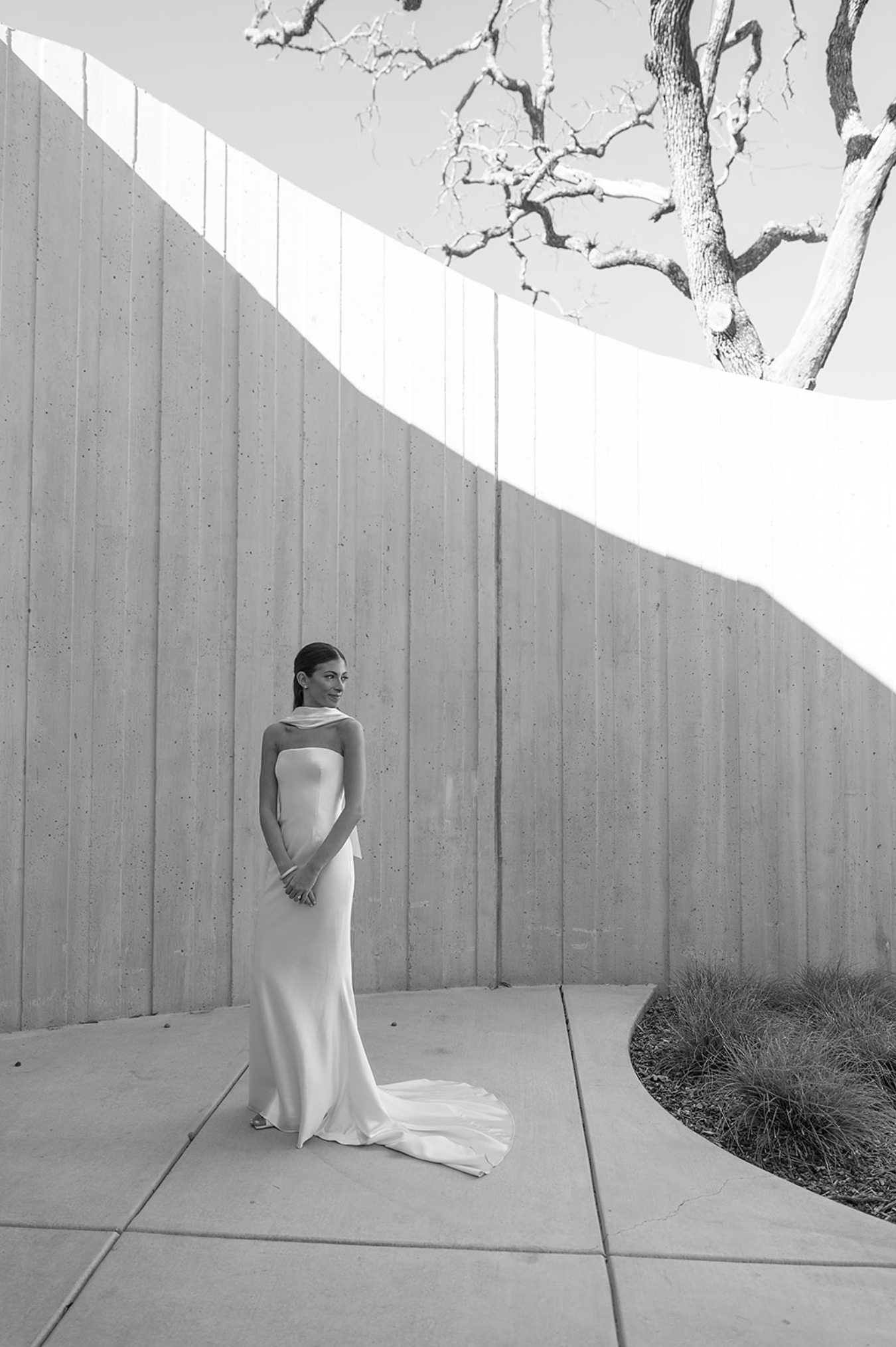 A series of black and white photos showing a figure in a flowing white dress moving against a light-colored wall.