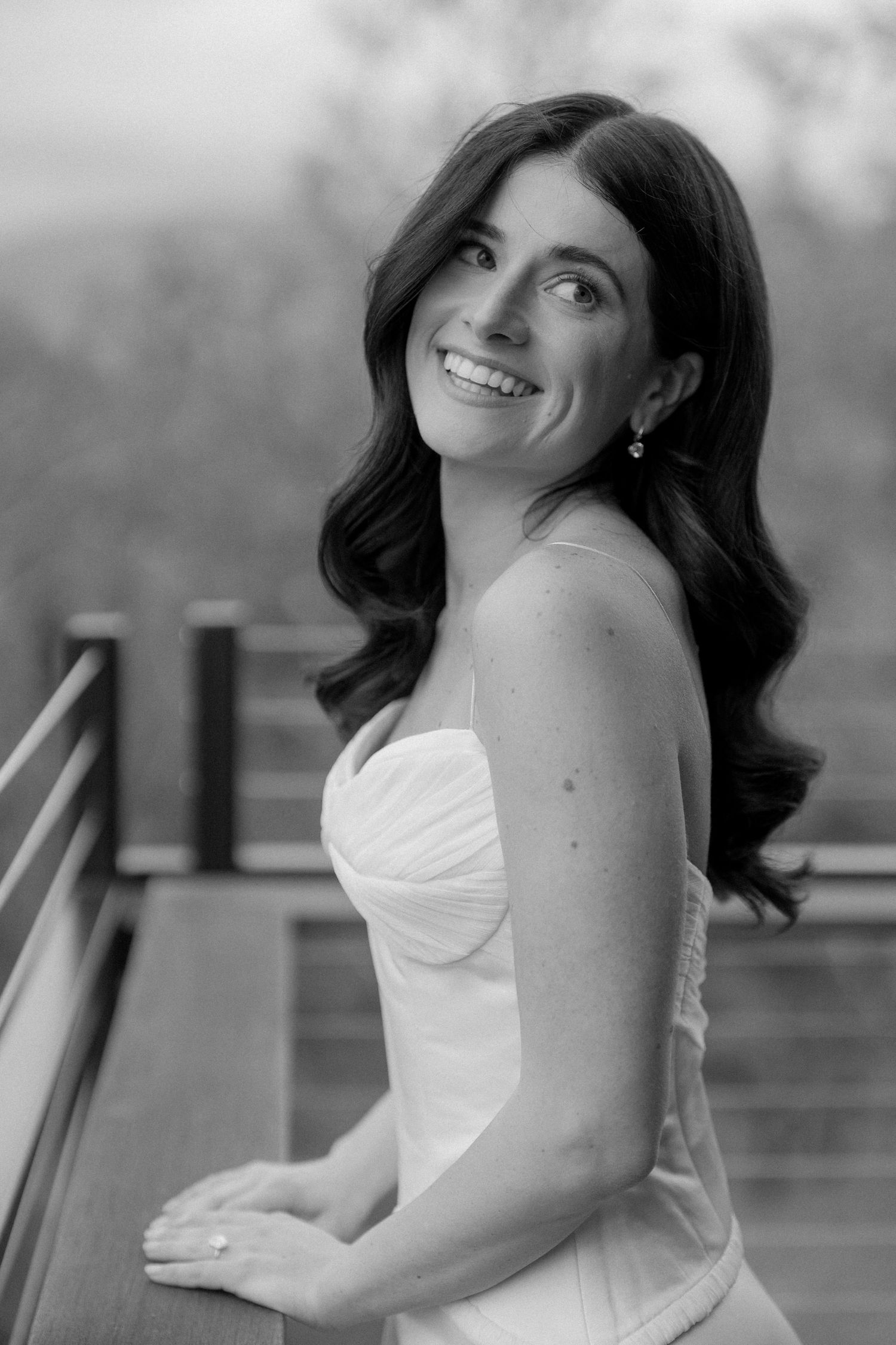 Person in a strapless white dress poses against an outdoor backdrop in black and white portraits.