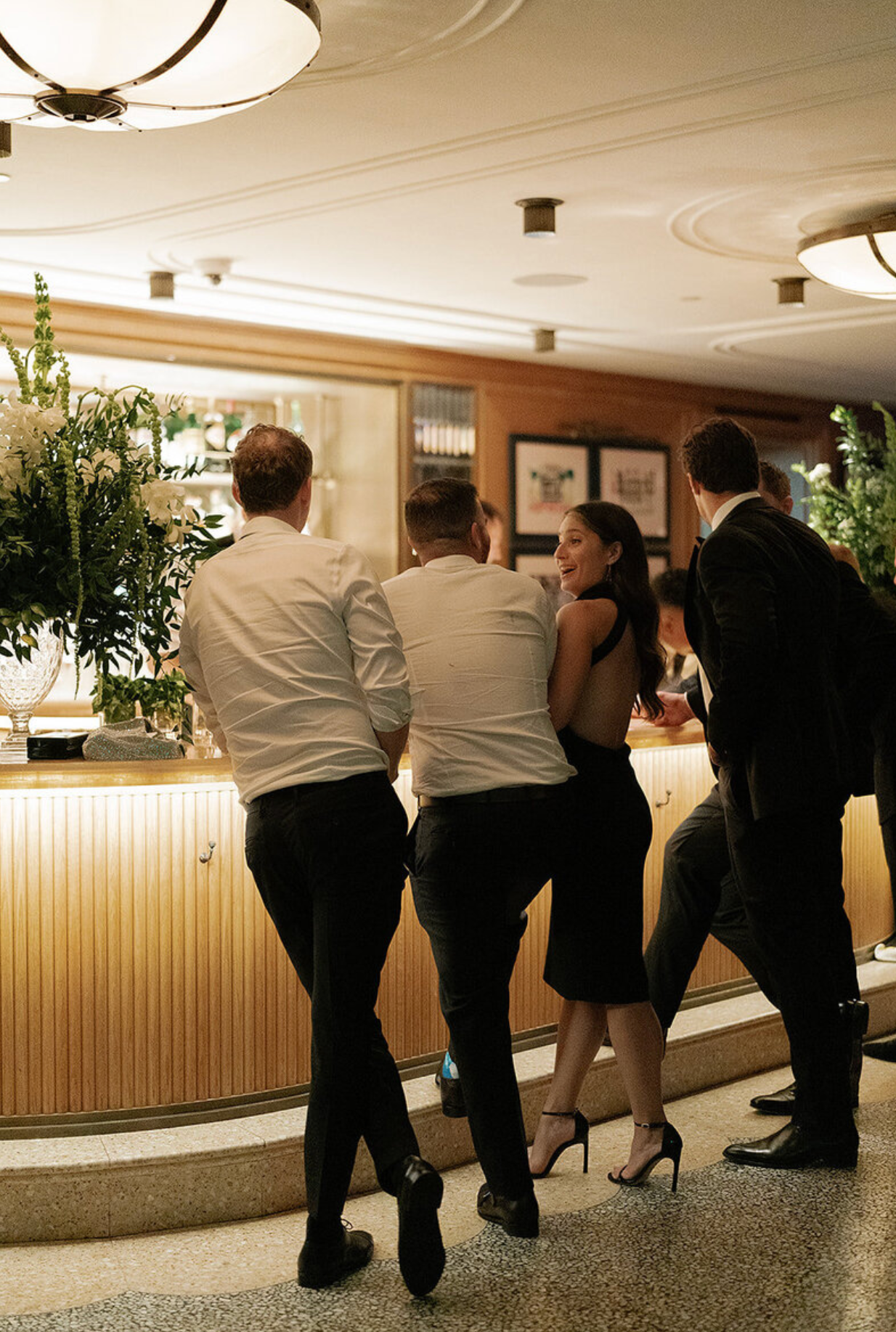 Wedding party members lined up against a wall in playful poses.