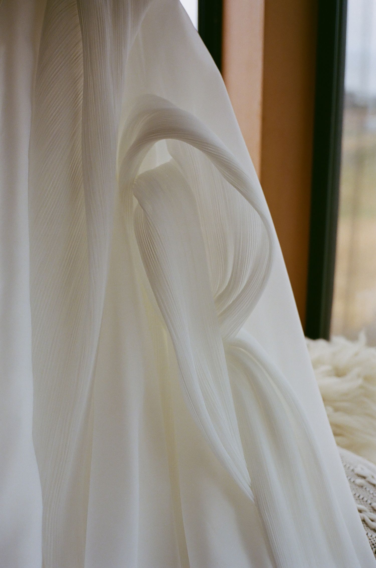 Close-up details of flowing white wedding dress fabric creating elegant folds and textures.