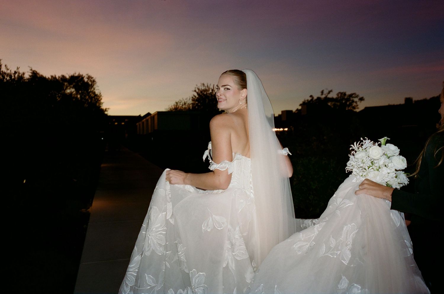 Silhouettes of a wedding party against a dramatic sunset sky.