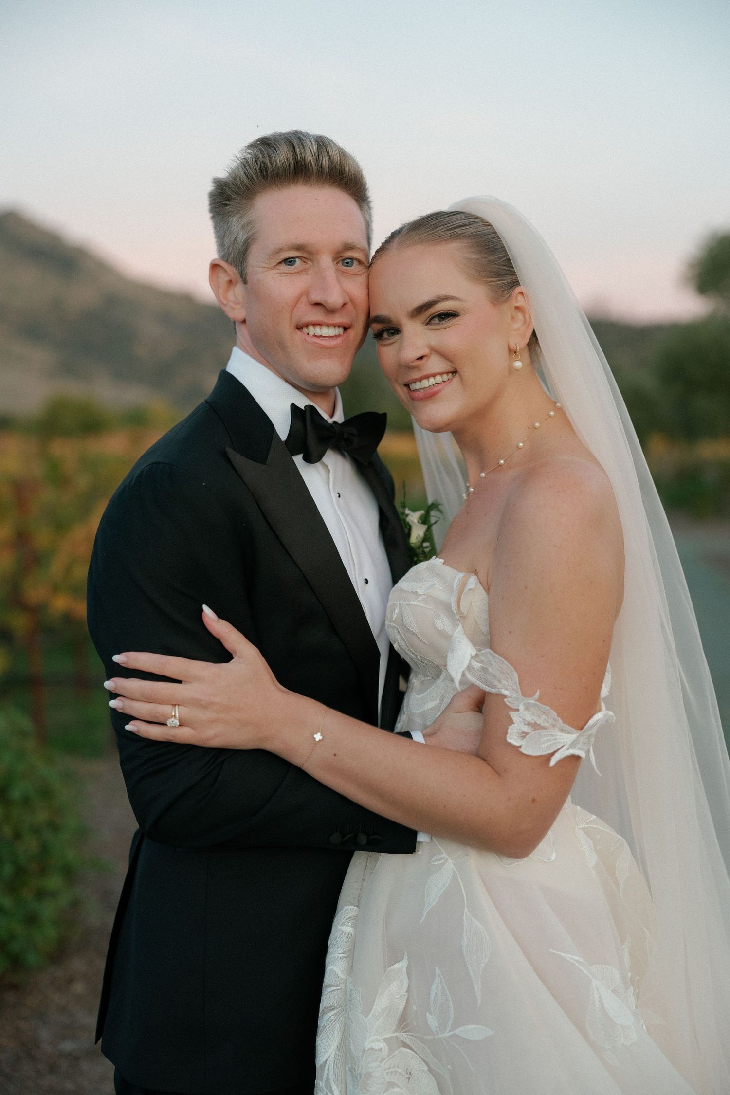 Romantic wedding portrait of newlyweds sharing a tender moment at sunset.
