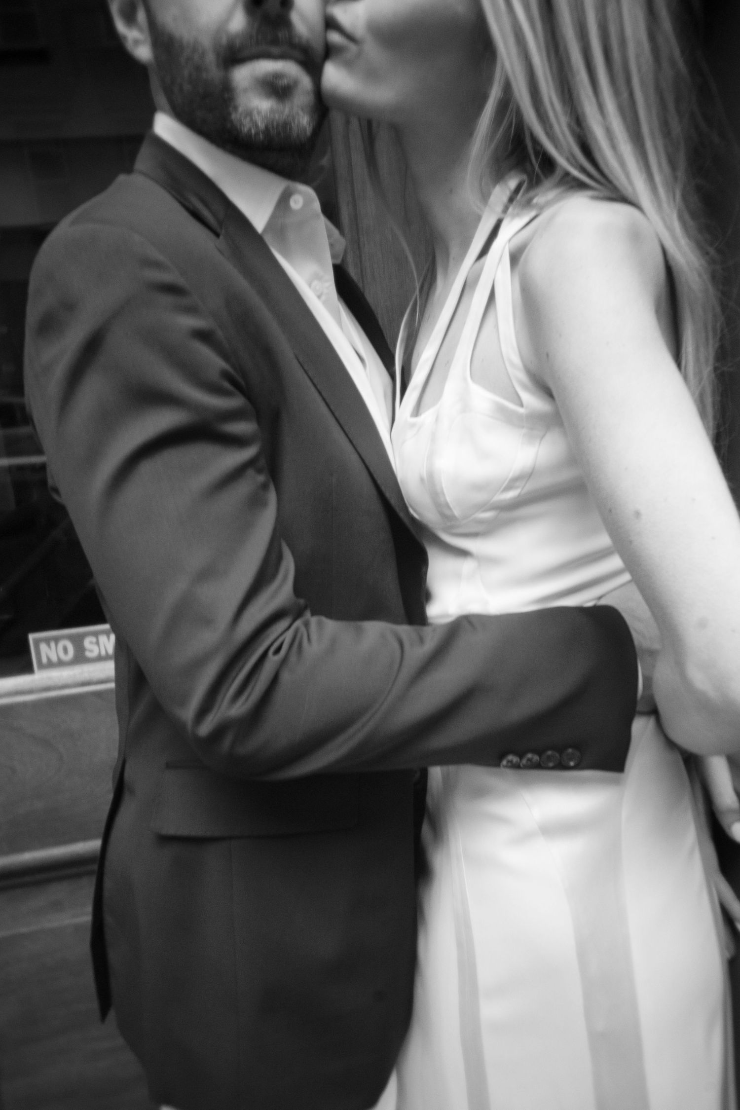 Black and white intimate portrait showing formal attire against urban backdrop.