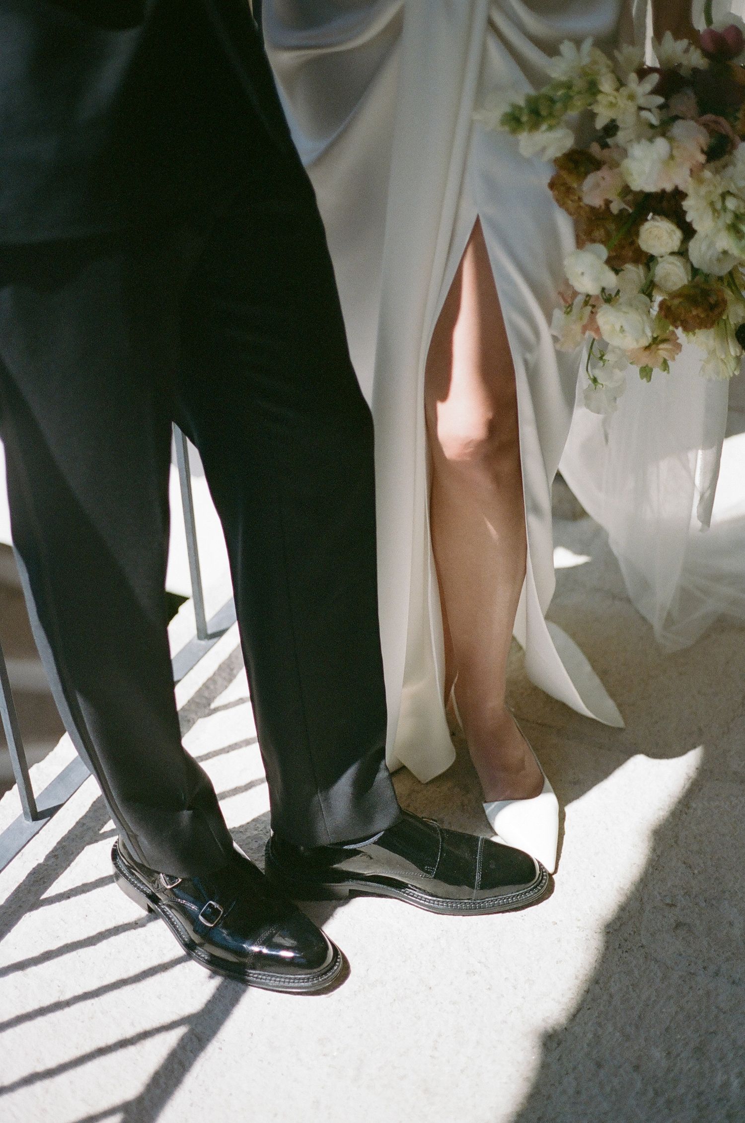 Formal black and white shoes and clothing captured in sunlight.