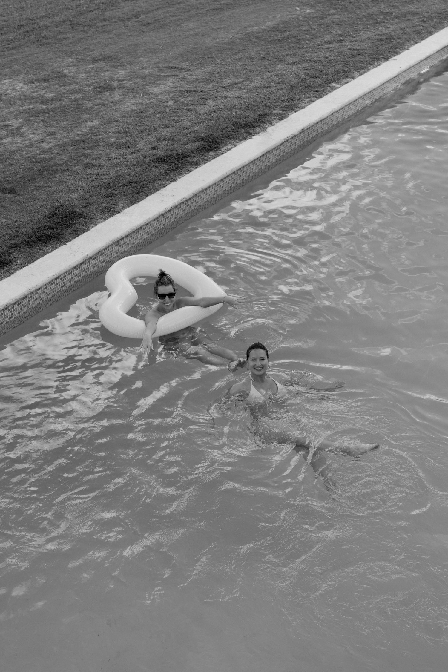 A black and white image of two people swimming in a pool.