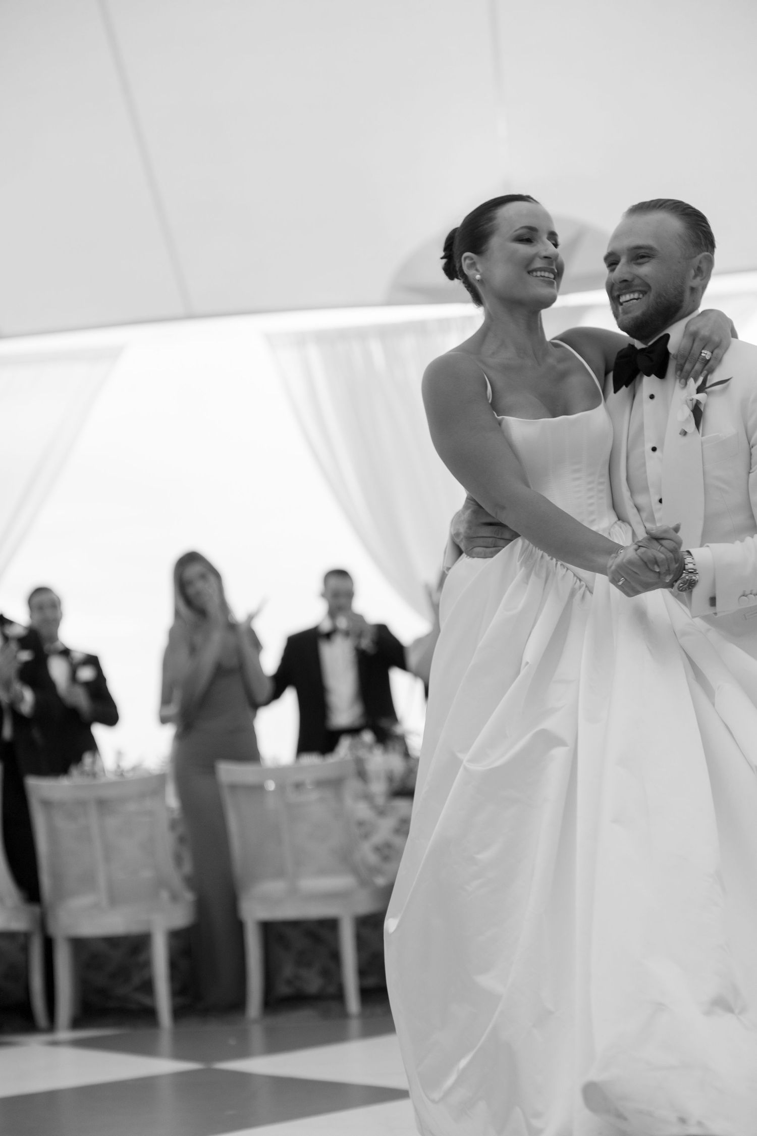 Joyful dancing moments captured during a wedding reception under a white tent.