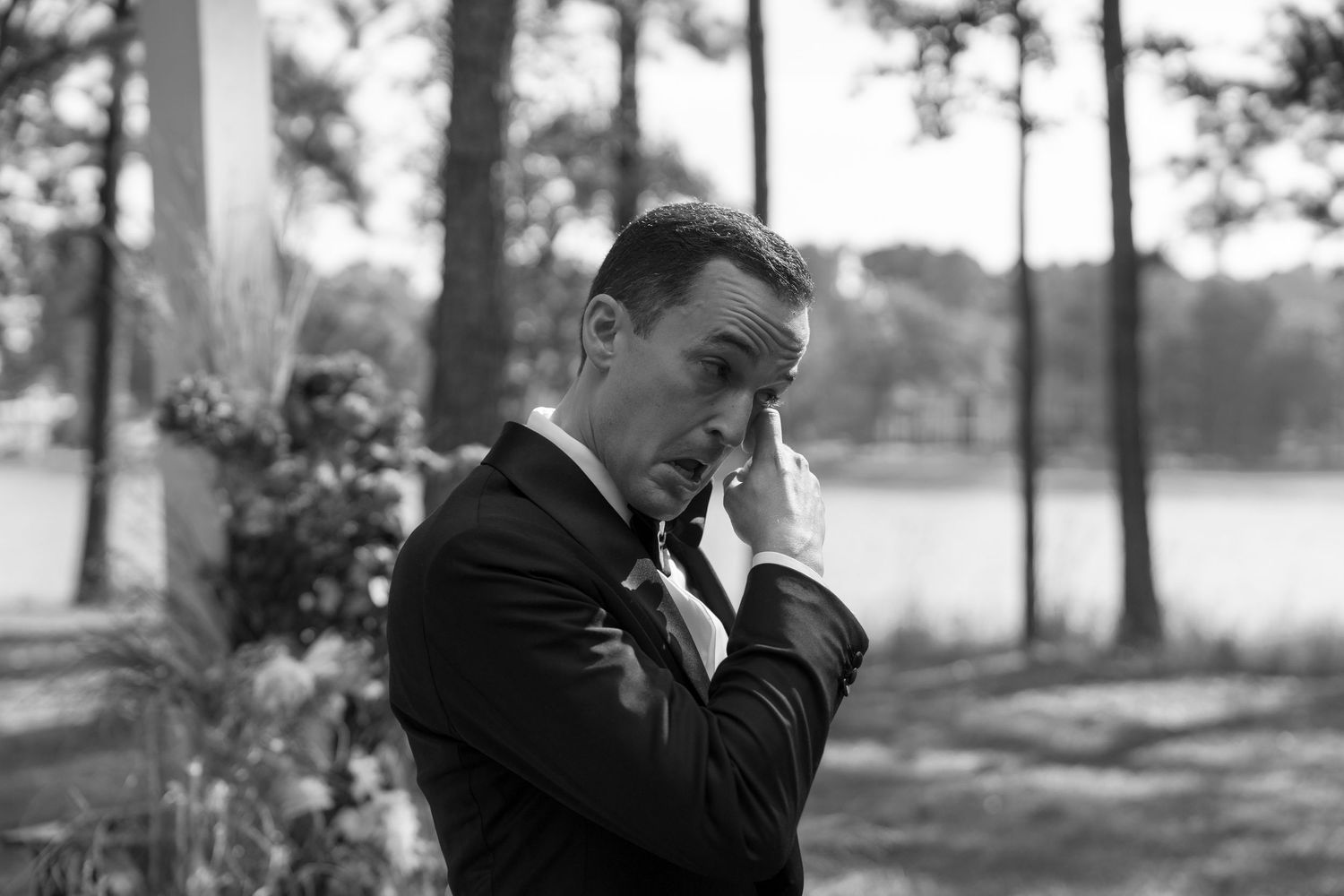 Black and white emotional moment captured during outdoor lakeside wedding ceremony.