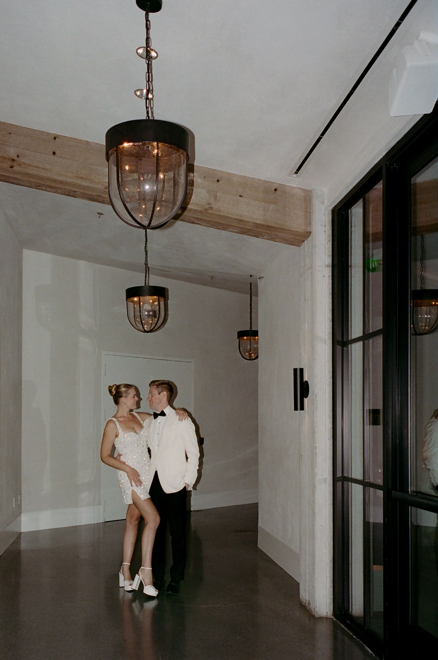 Modern hallway with glass panels and pendant lights creating dramatic shadows.