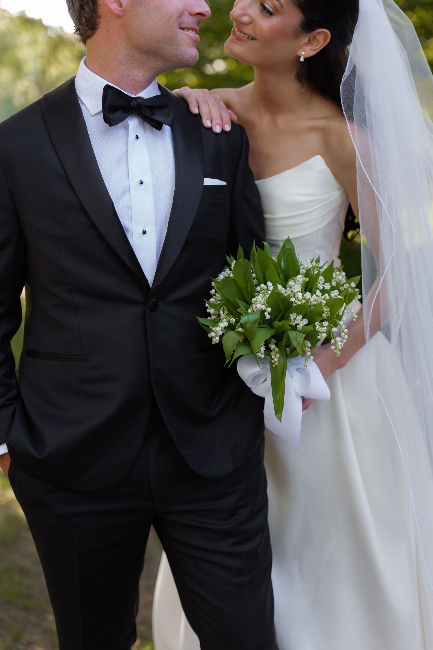 Bride and groom walking together holding lily of the valley bouquet.