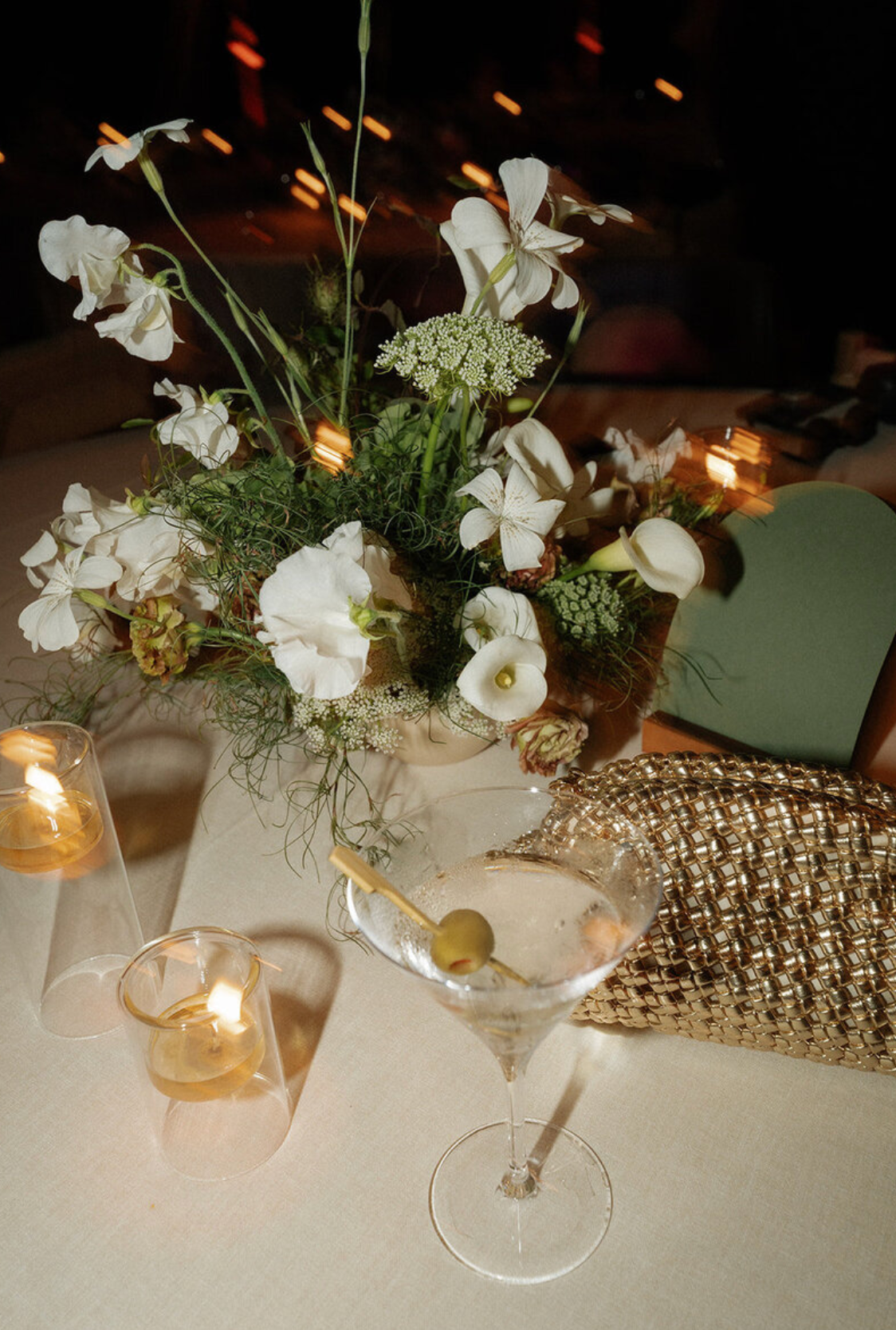 White floral centerpieces with delicate blooms arranged in crystal glasses on a textured table runner.