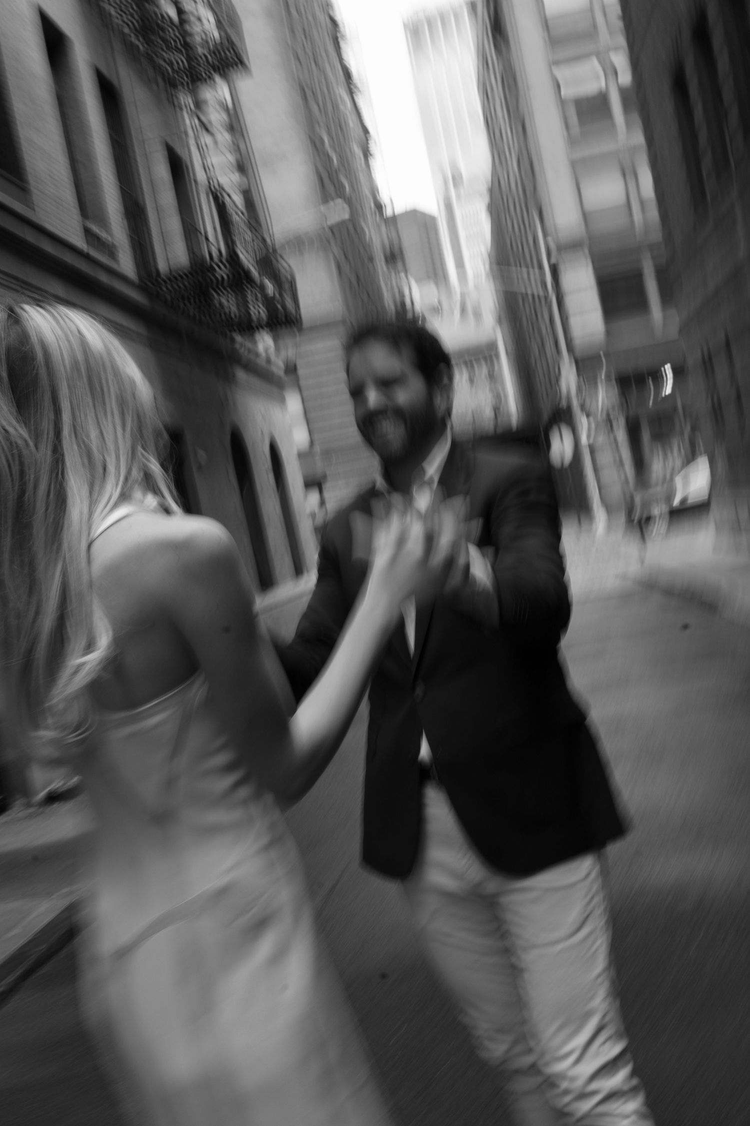 Motion-blurred black and white photo of a couple dancing on a city street.