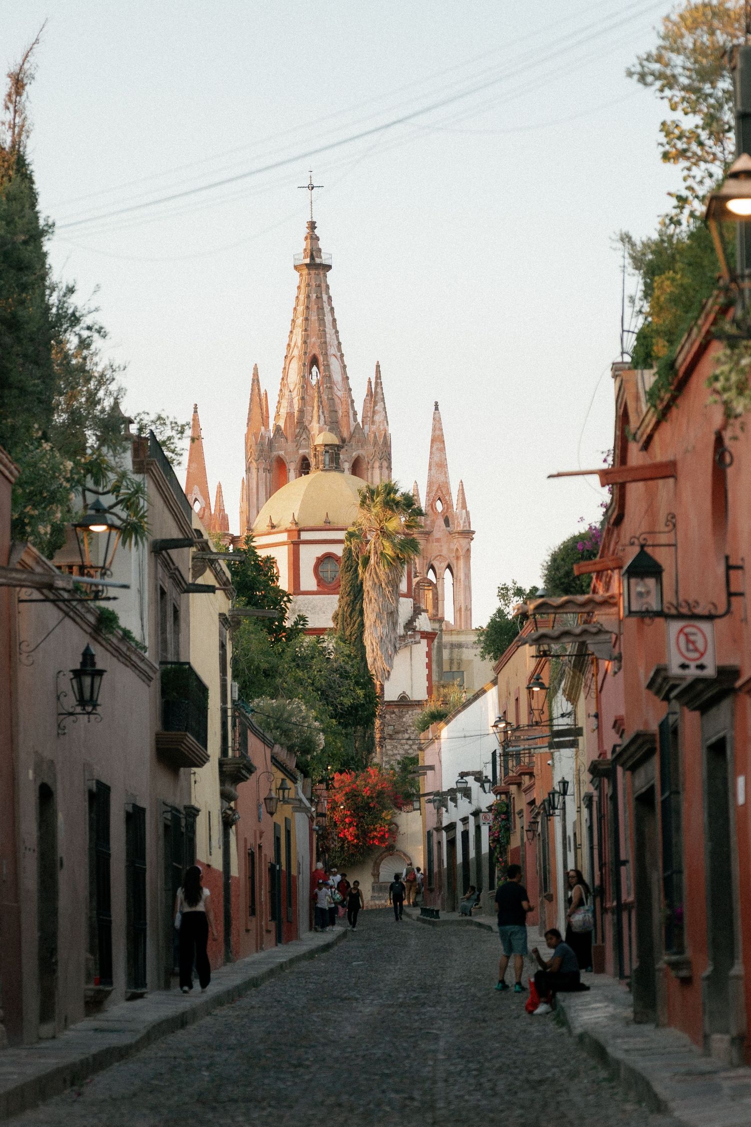 Charming cobblestone street in San Miguel de Allende with colonial architecture and church spires in the background.