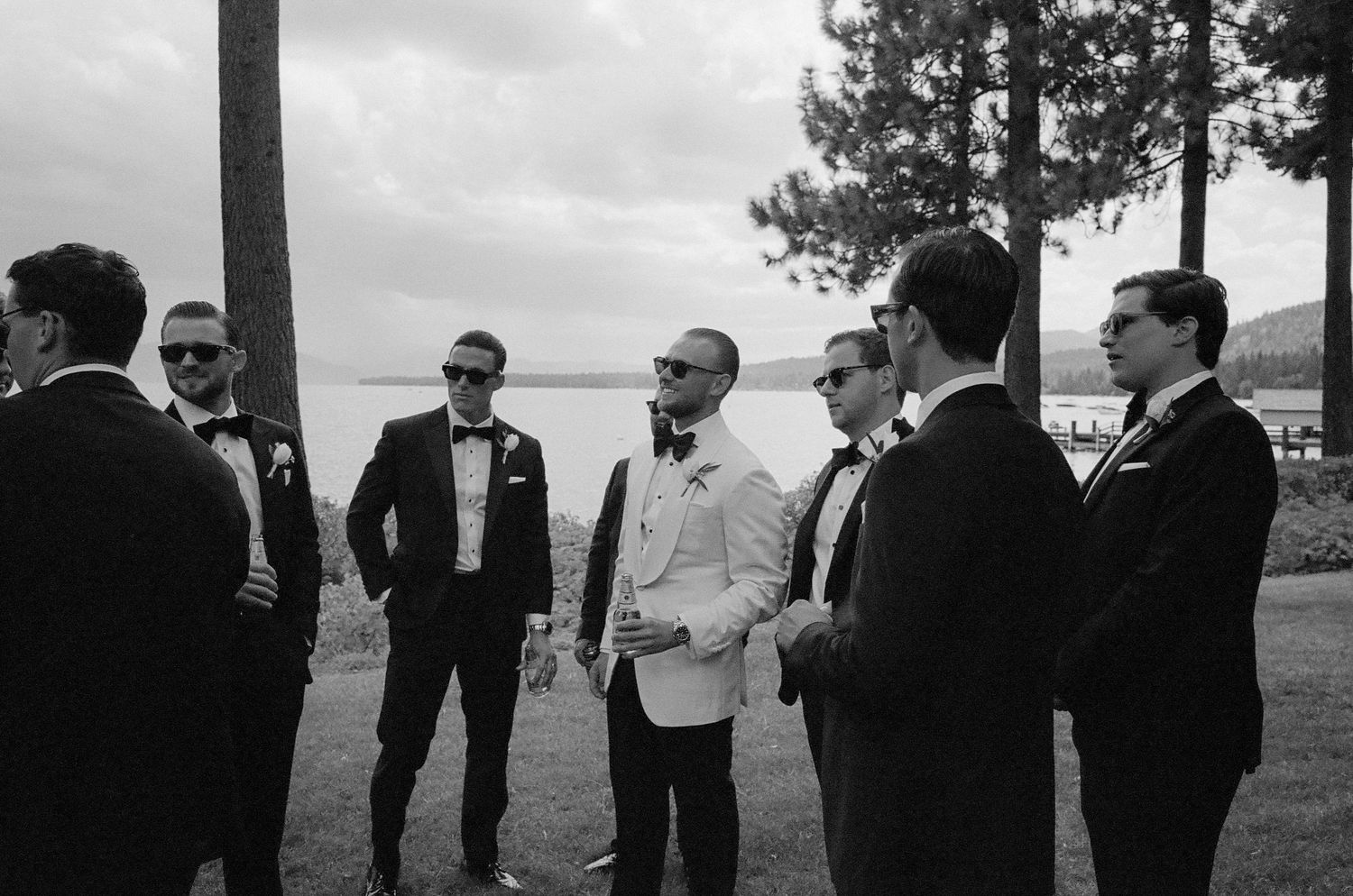 Group gathered outdoors in formal attire against a cloudy mountain backdrop.