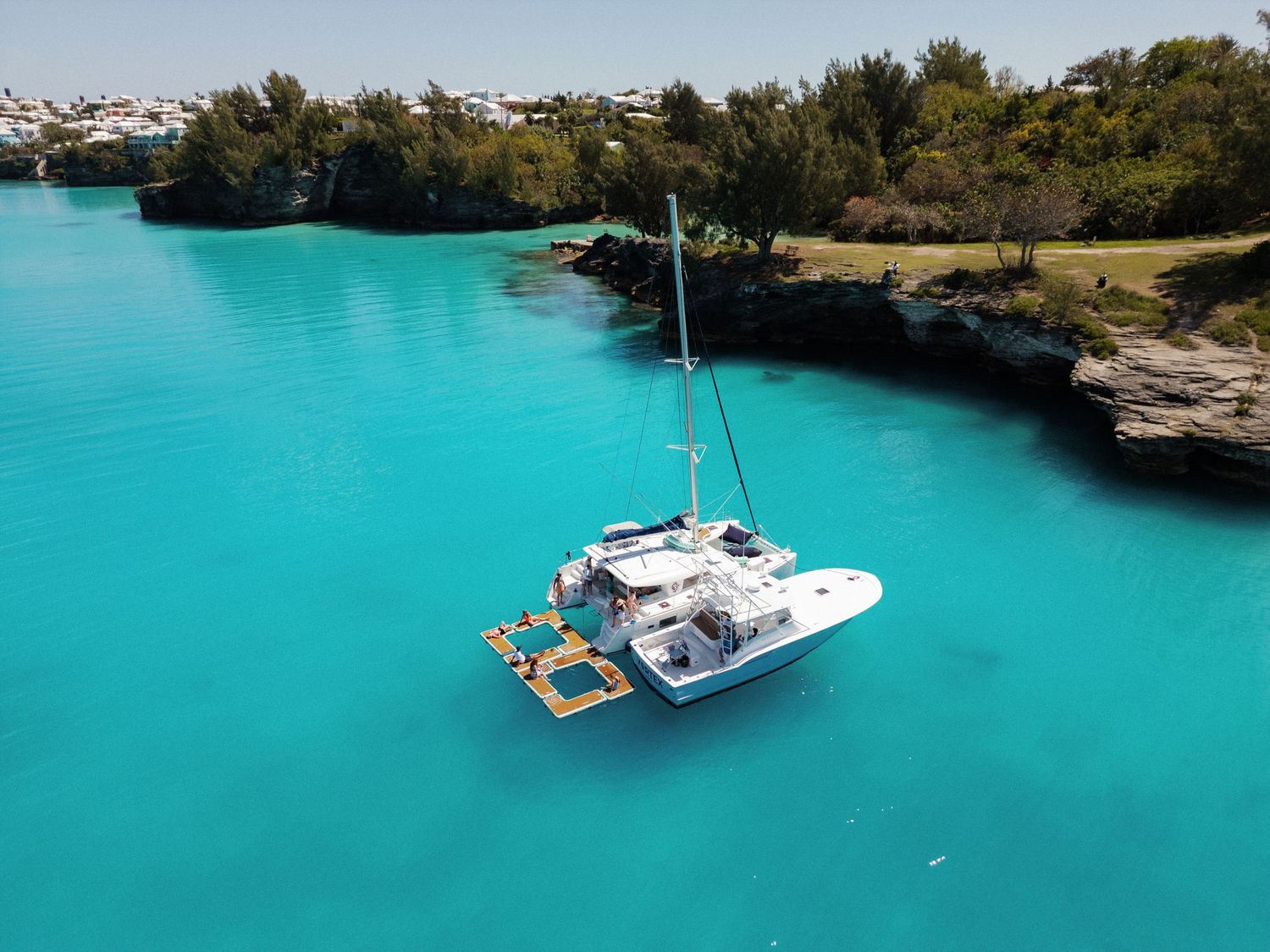 A sailboat floating on a vibrant turquoise body of water surrounded by lush greenery.
