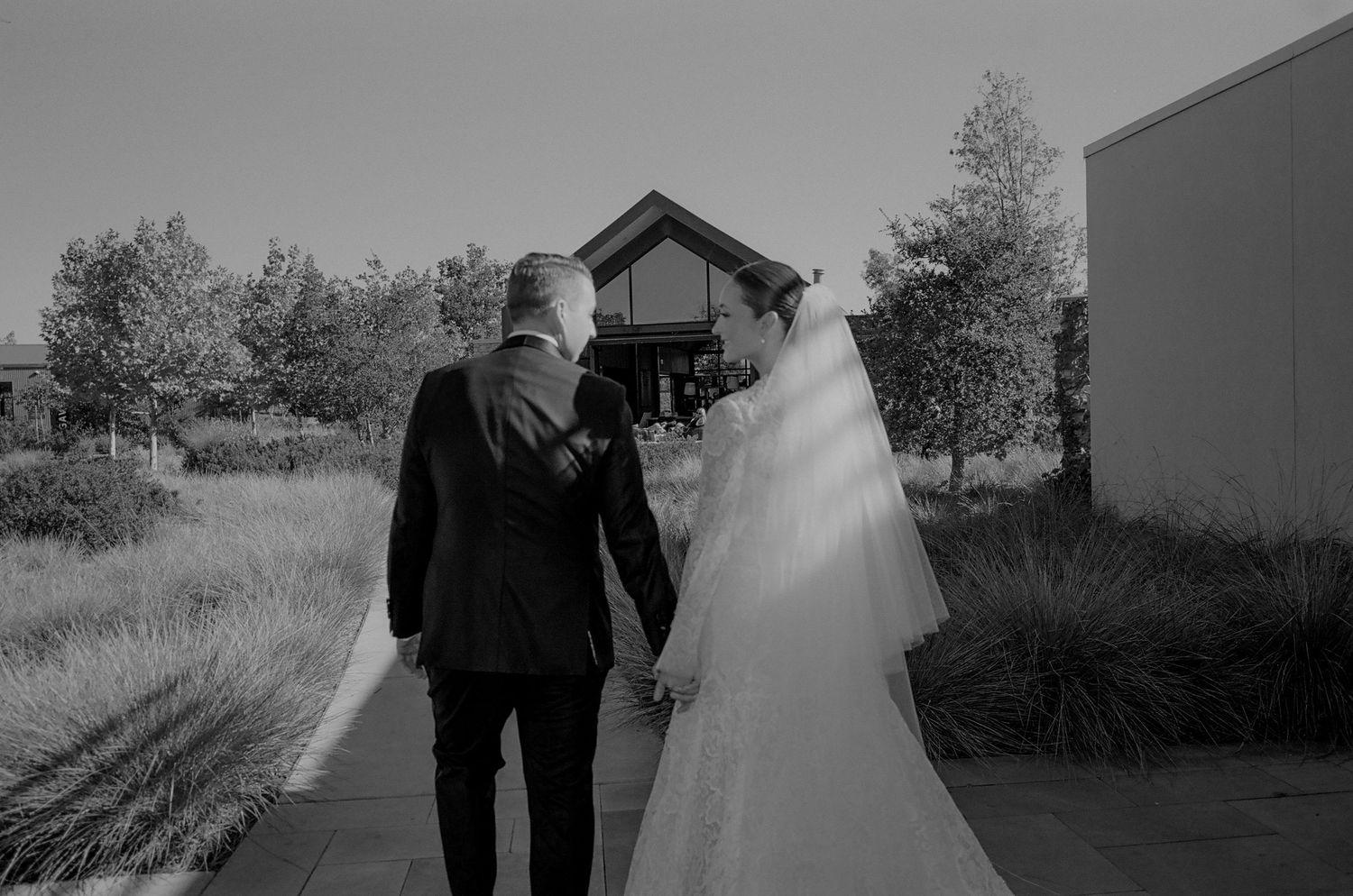 Black and white wedding photo of a couple walking together outdoors.