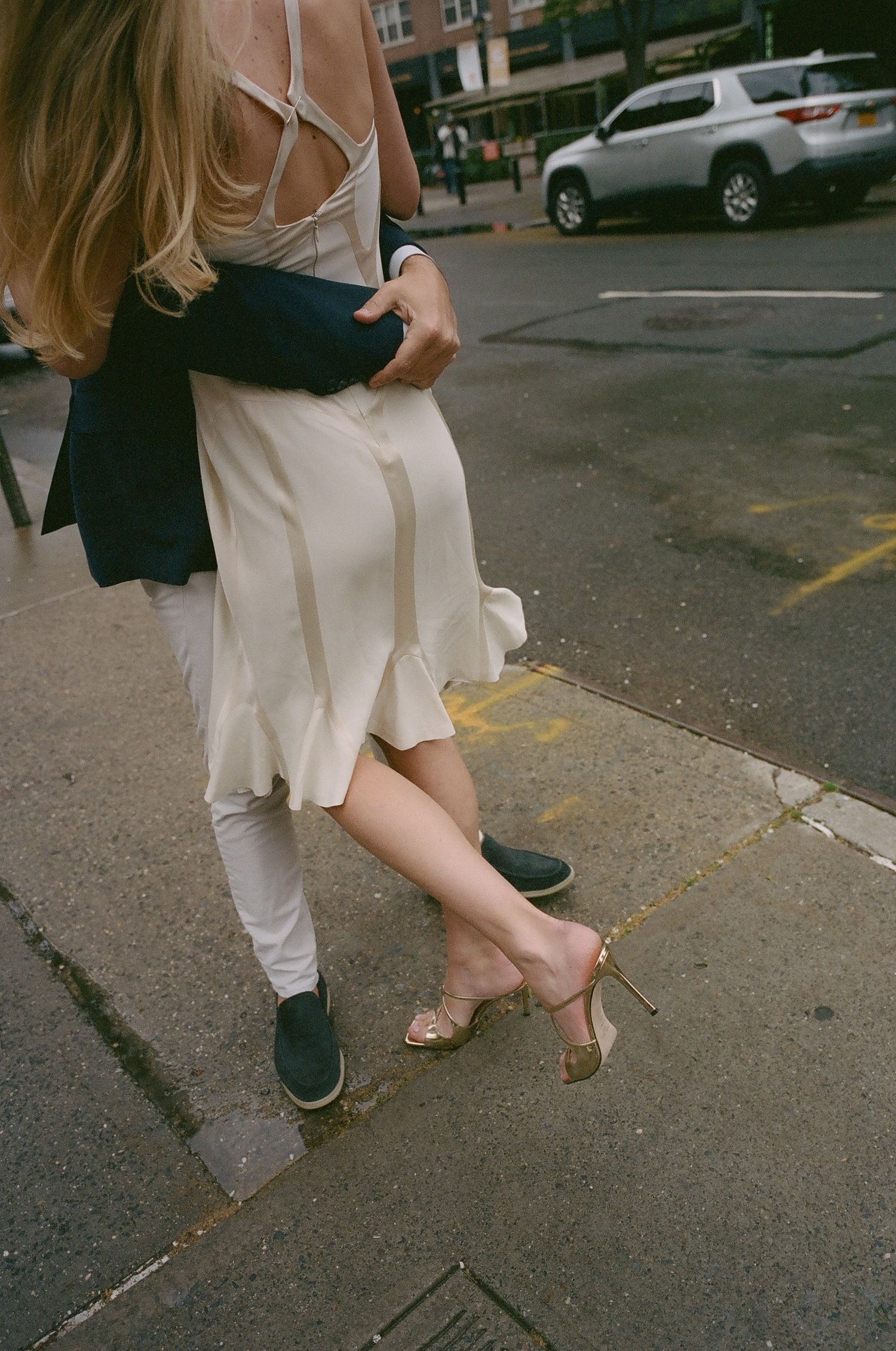 Dancing feet and flowing dress captured on a city sidewalk.