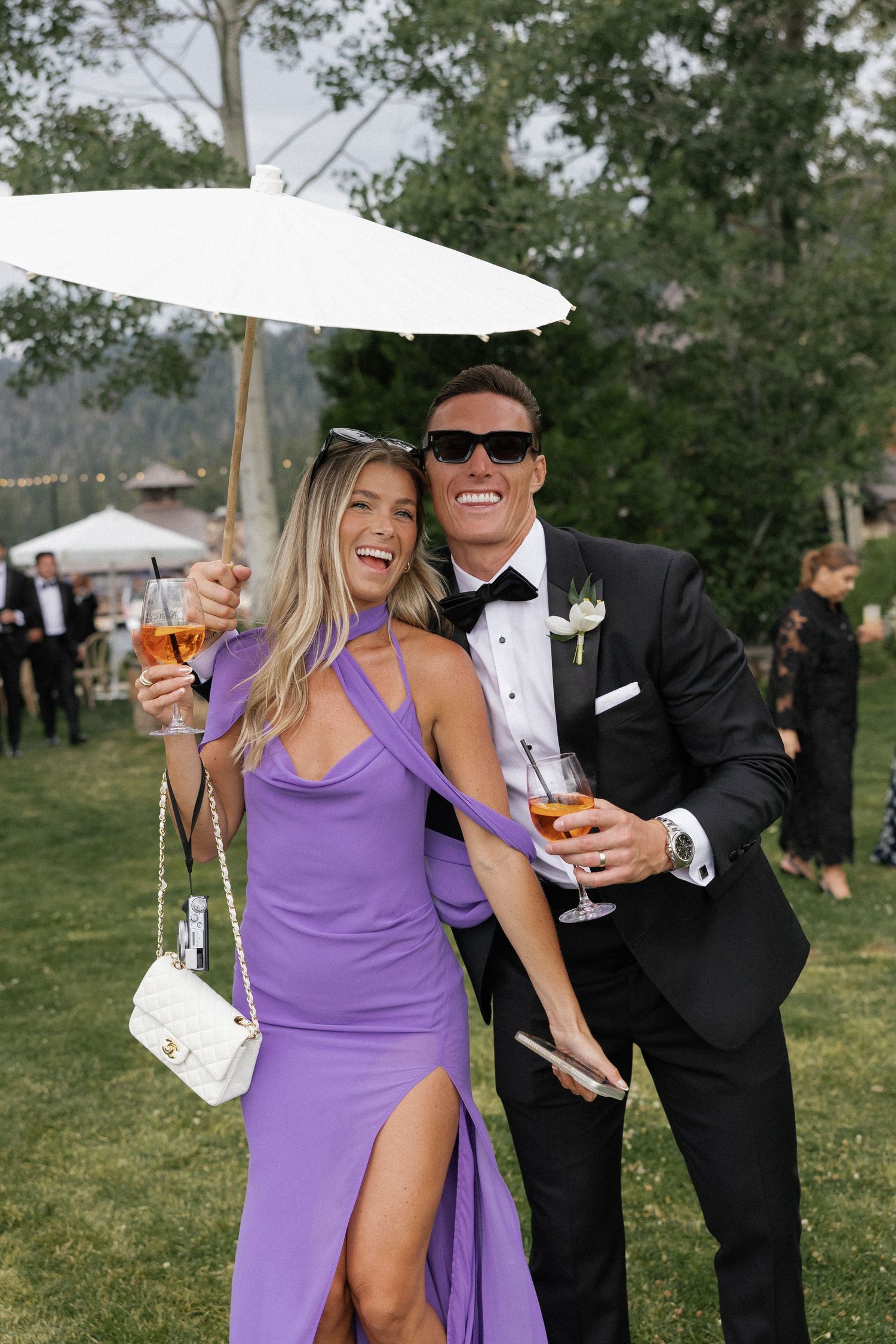 Wedding celebration on a lawn with guests in formal attire enjoying cocktails.