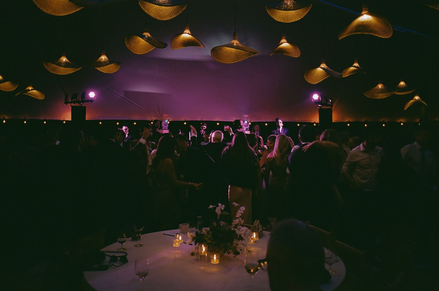 Wedding reception venue with ambient lighting and hanging decorations at night.
