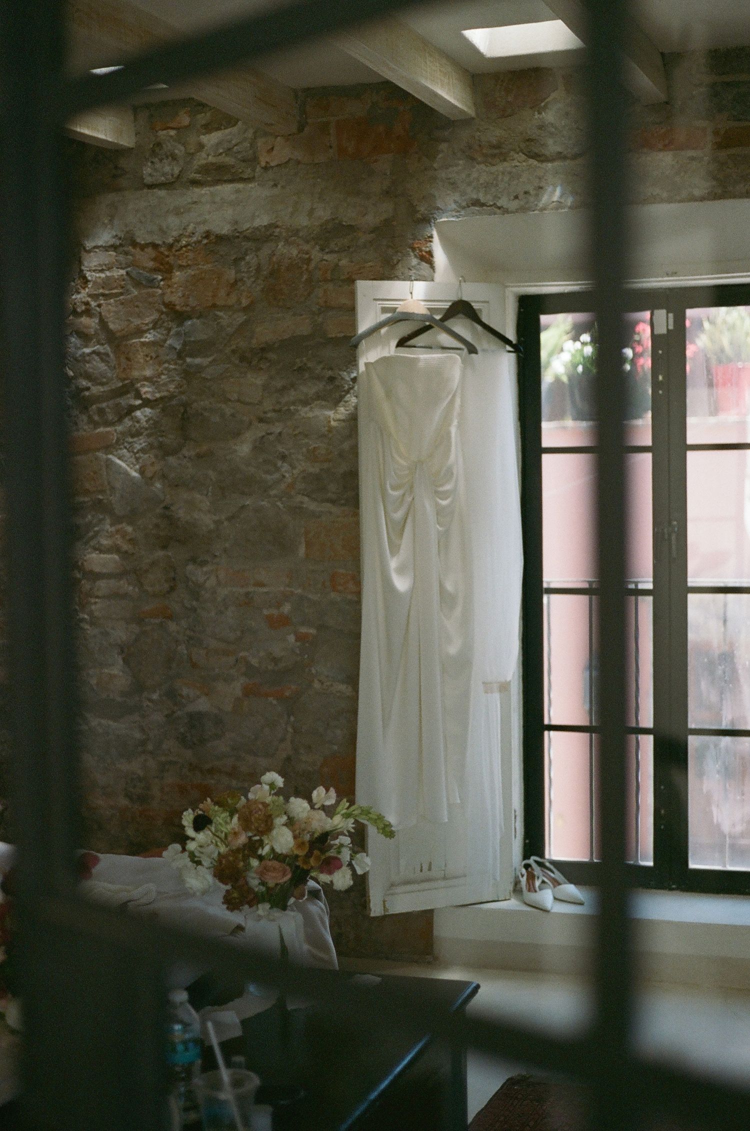 Interior room with stone walls and white curtains hanging by large windows creating a moody atmosphere.