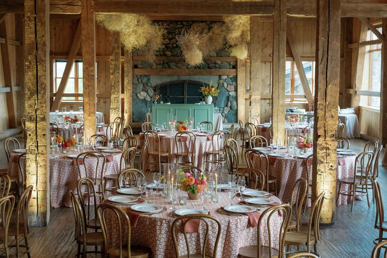 Rustic wooden reception hall with elegant table settings and natural light streaming through windows.