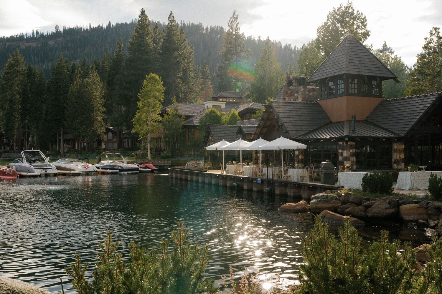 Scenic lakefront view of mountain cabins and docks along a tree-lined shore.