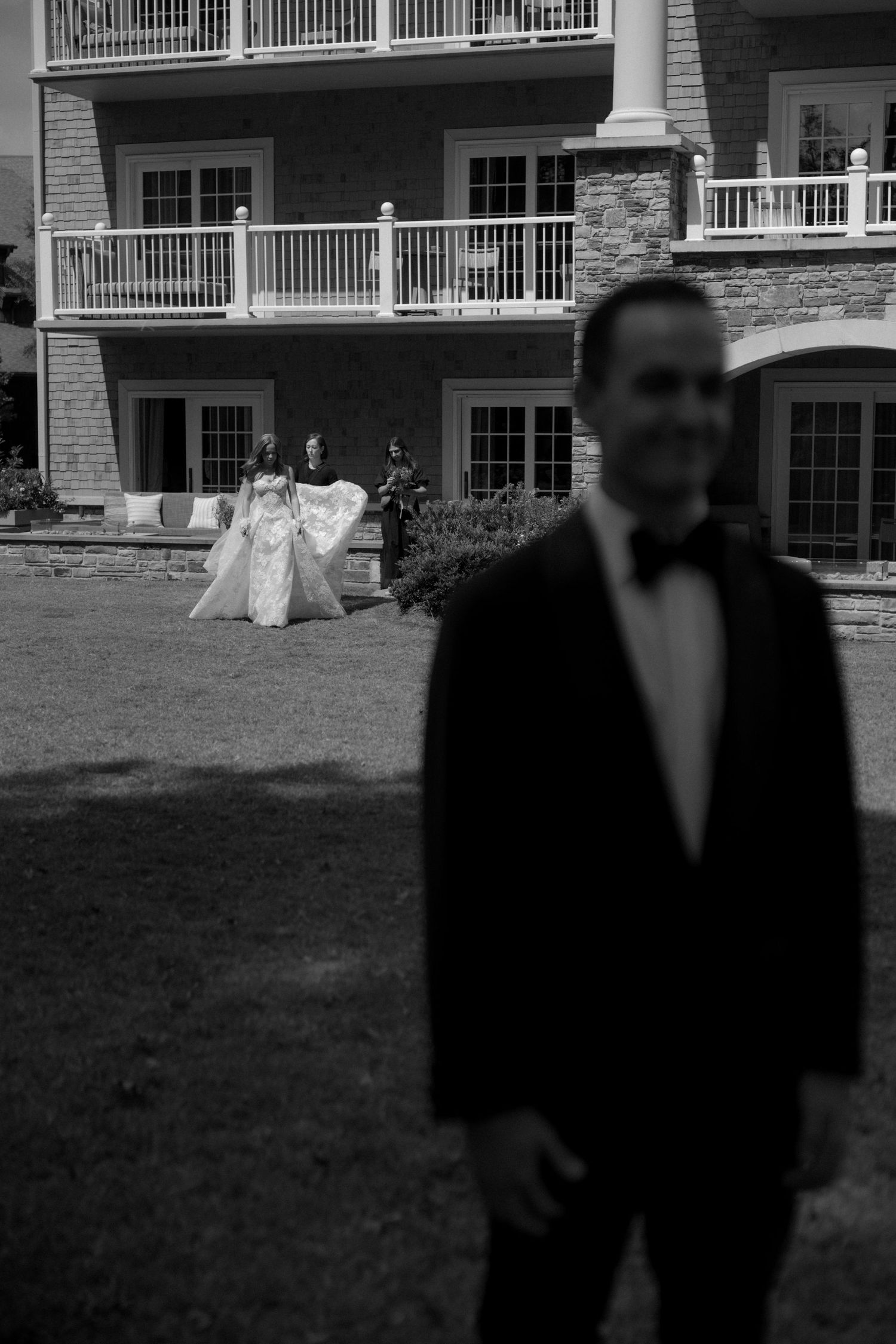 Black and white wedding photo with large building and balconies in background.