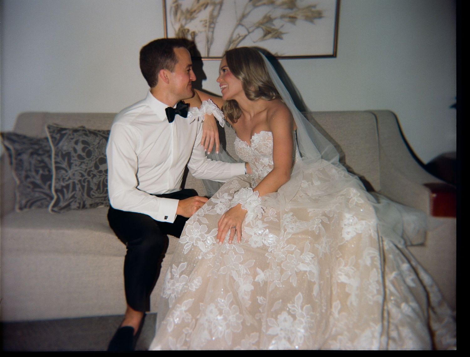 Romantic moments captured on a white couch during wedding celebrations.