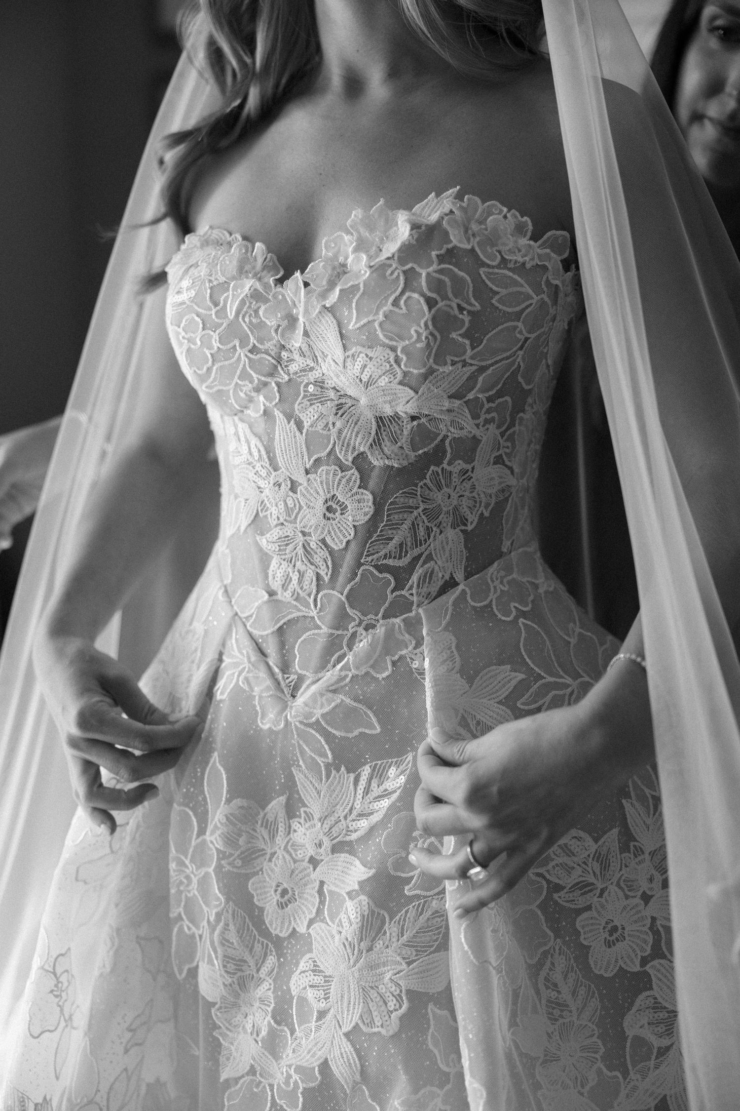 Close-up detail of a white lace wedding dress bodice with floral patterns.