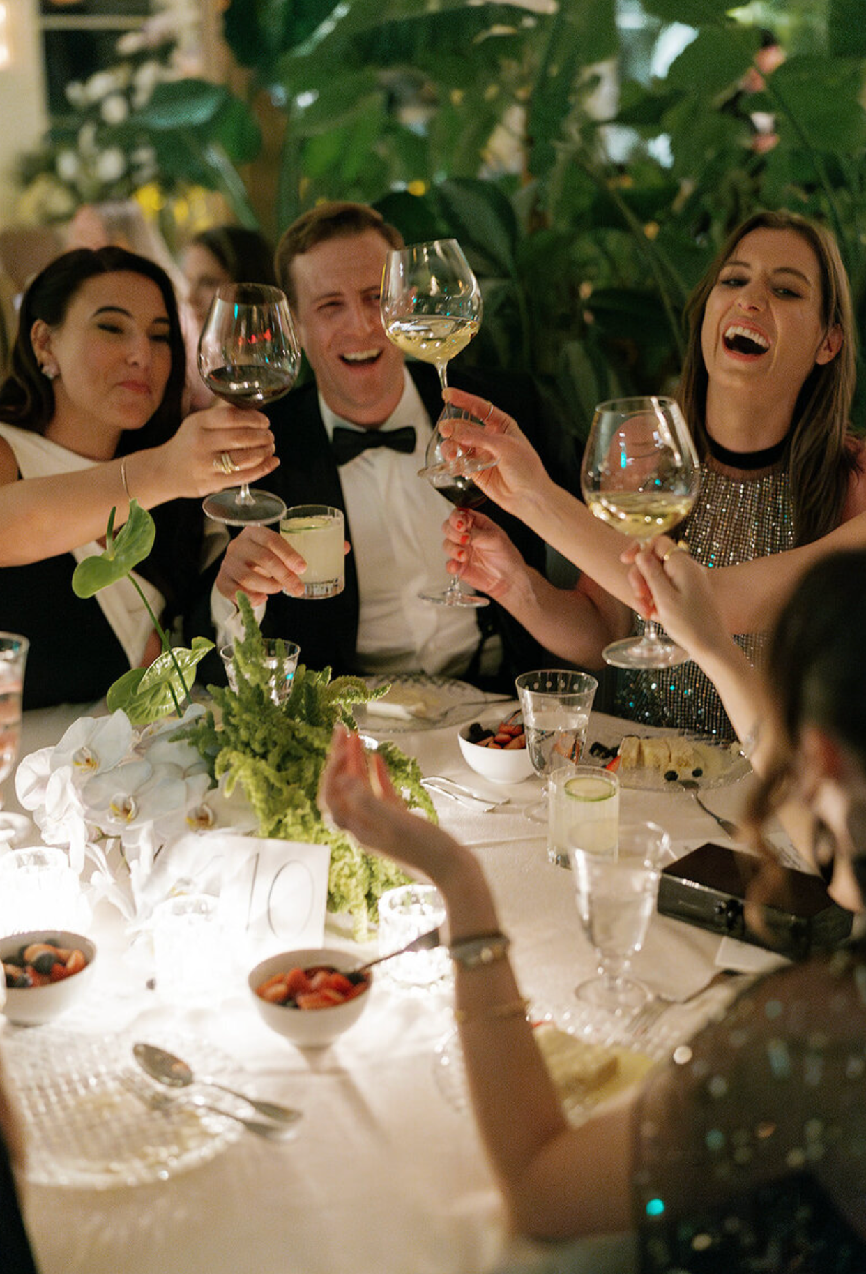 Wedding reception guests toasting with wine glasses at an elegantly set dinner table.