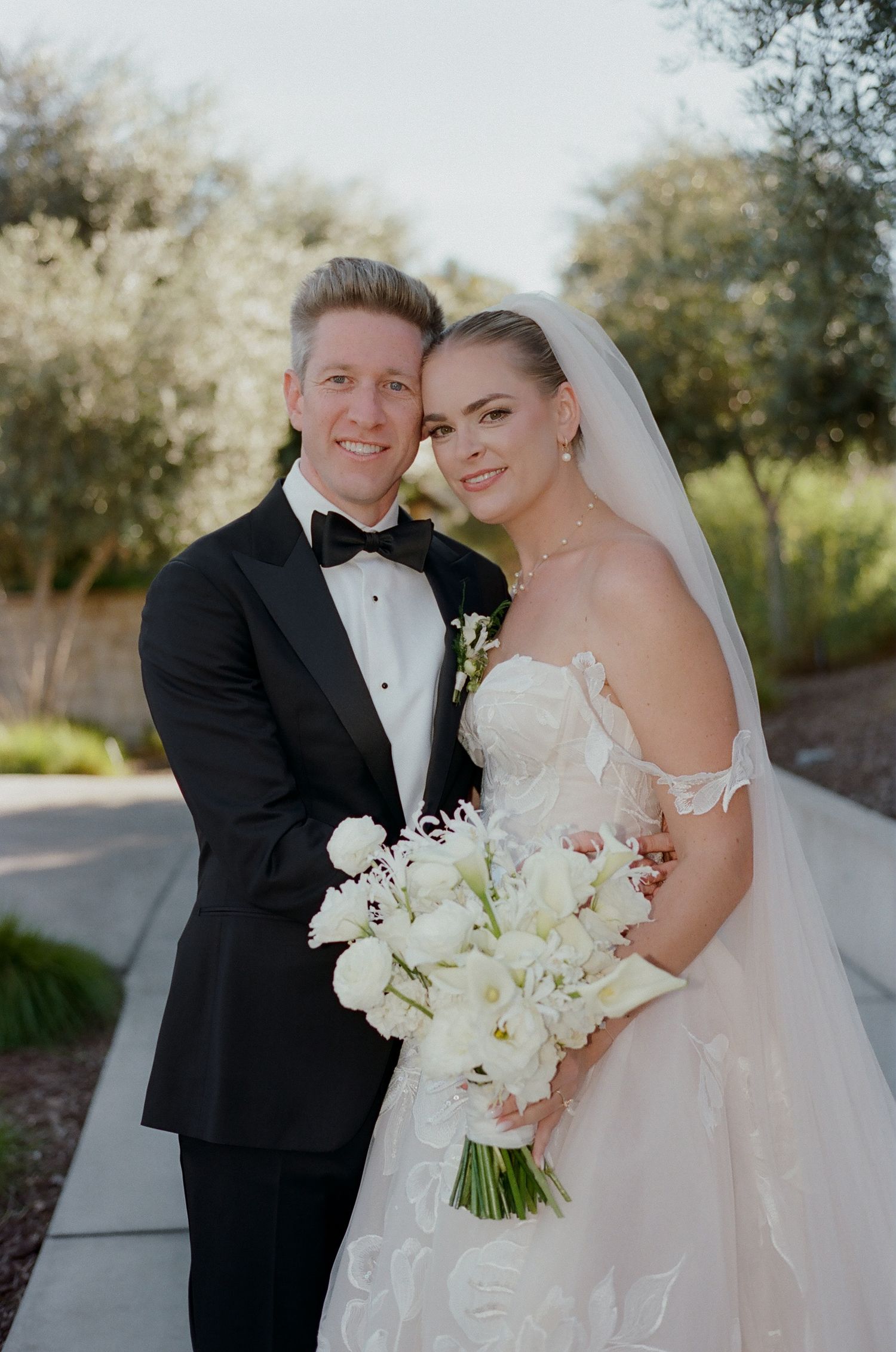 A wedding portrait outdoors with white floral bouquet.
