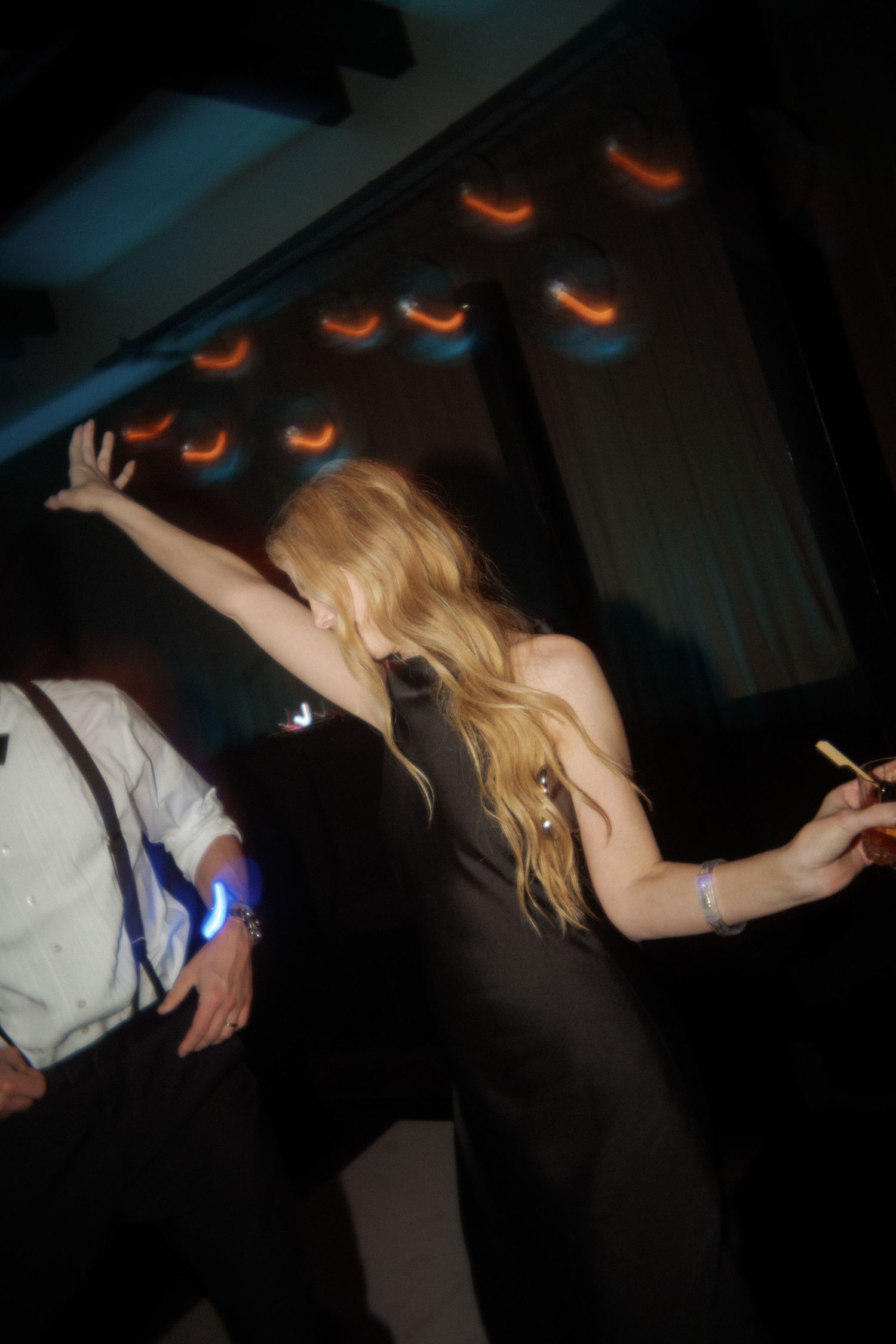 Dancers in formal attire performing energetic moves under dramatic lighting.