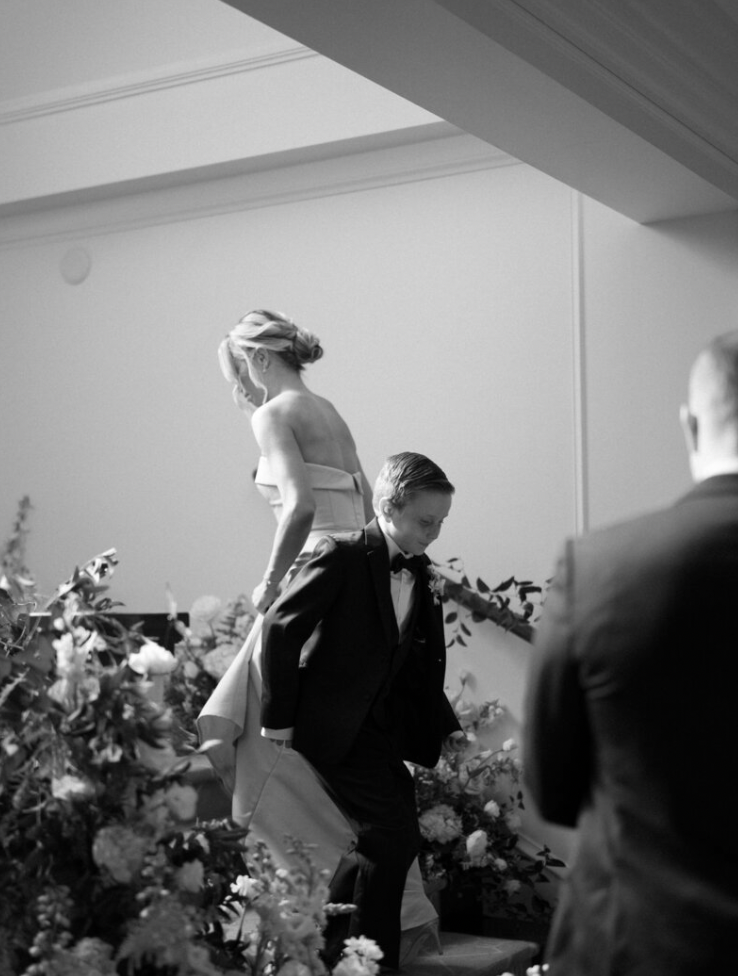 Black and white candid moments from a wedding reception with floral arrangements in foreground.