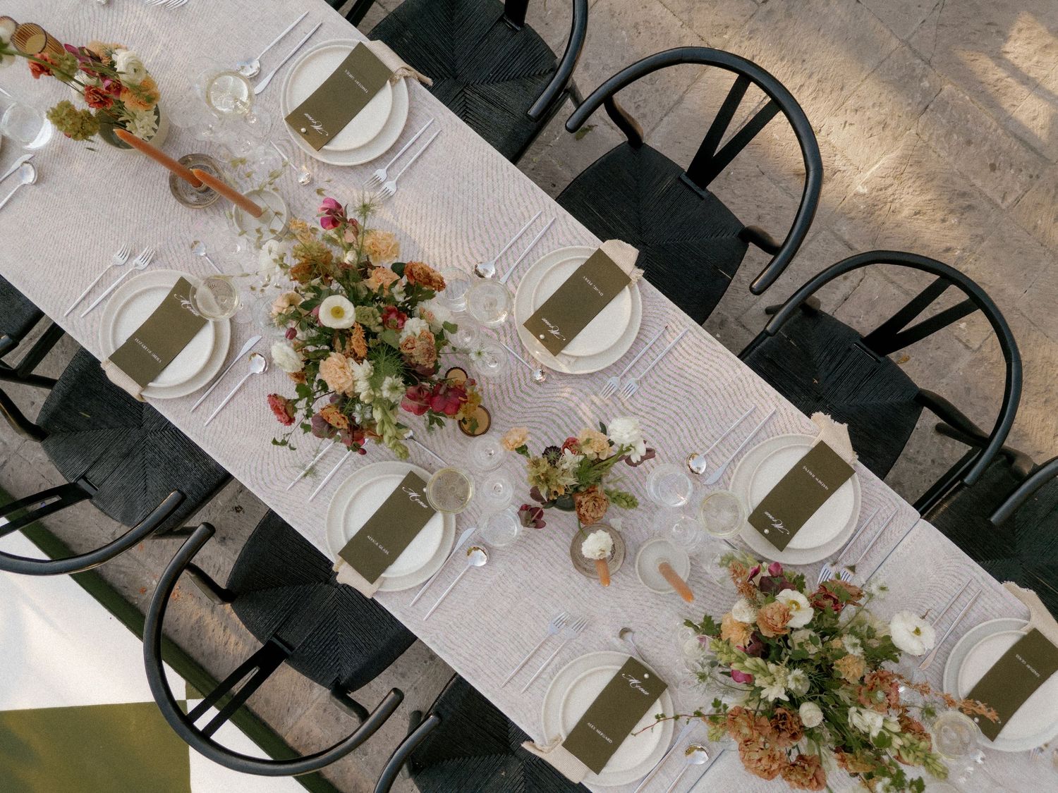 Elegant wedding reception table setting with floral centerpieces and place settings.