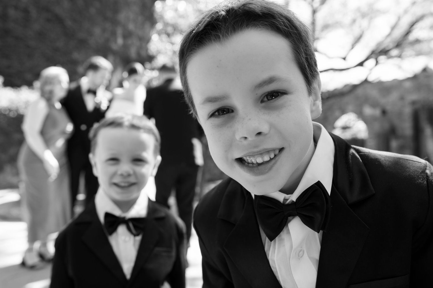 Two young boys in formal black bow ties at an outdoor celebration.