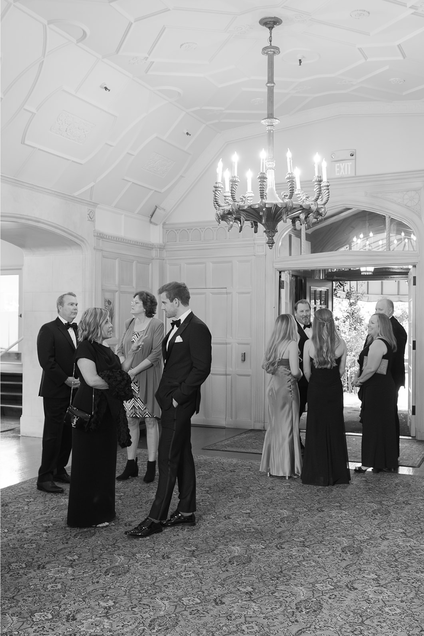 Formal gathering in an elegant white ballroom with chandeliers and classic decor.
