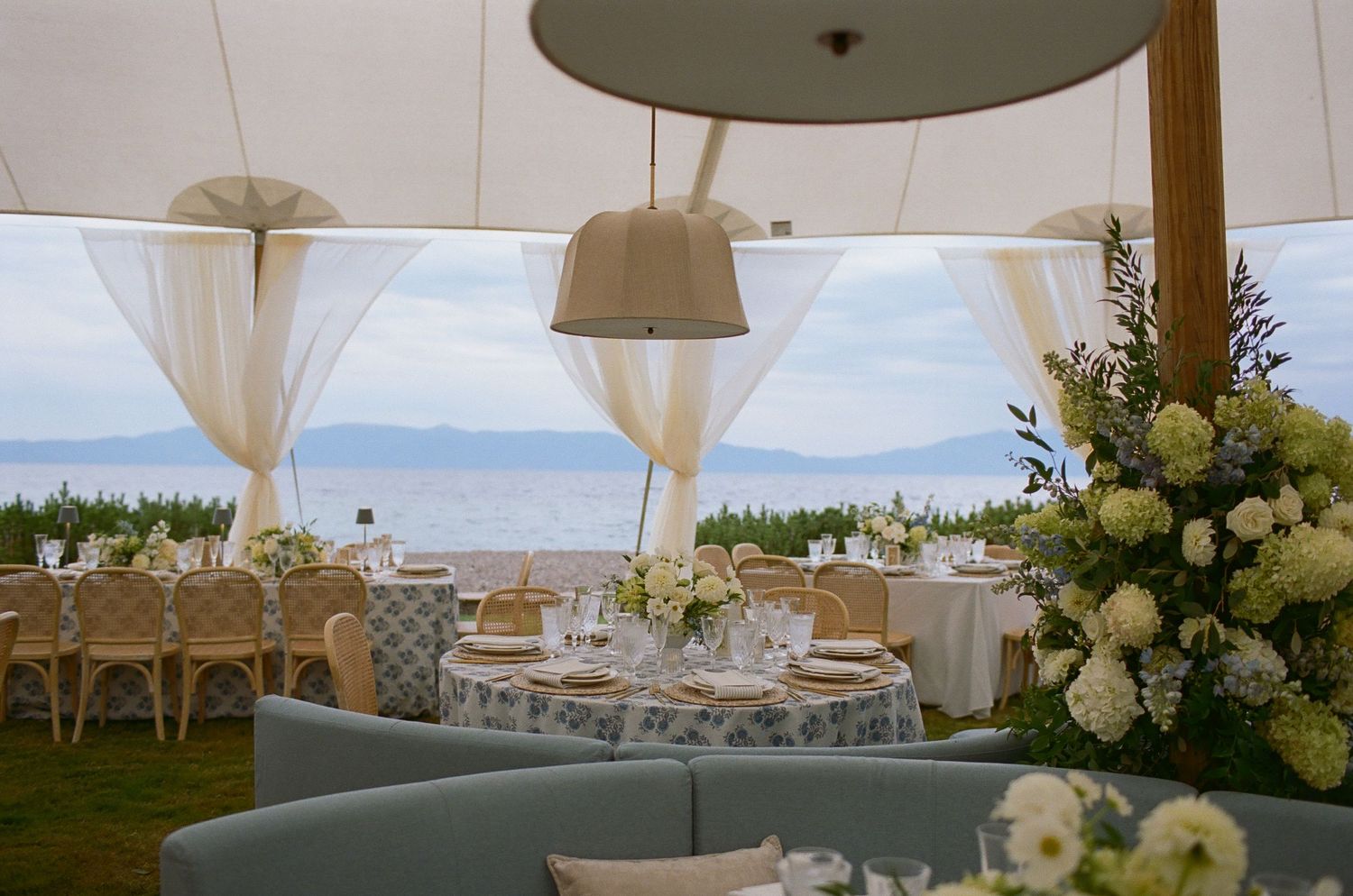 Elegant wedding reception setup with white tents, floral arrangements, and lakeside views.