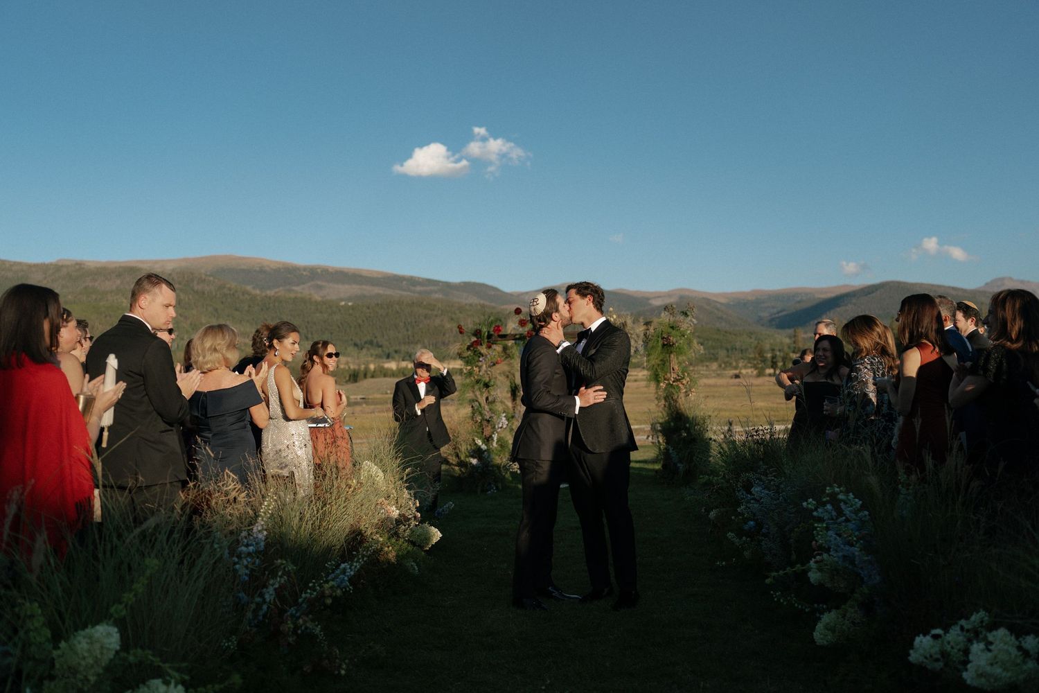 Outdoor wedding ceremony guests seated with mountain landscape in background.