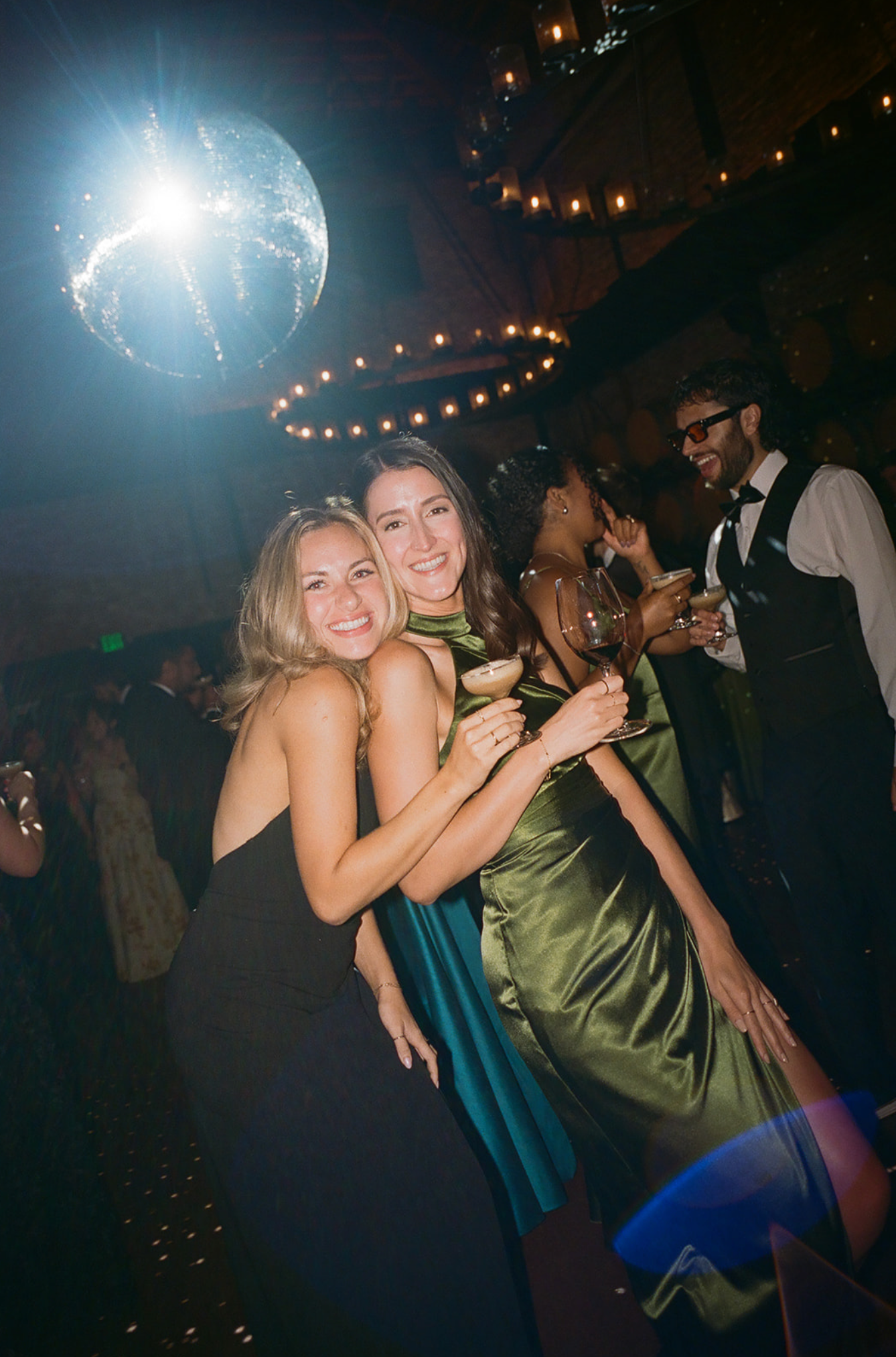 Wedding reception dance party with string lights and dancing guests in formal attire.