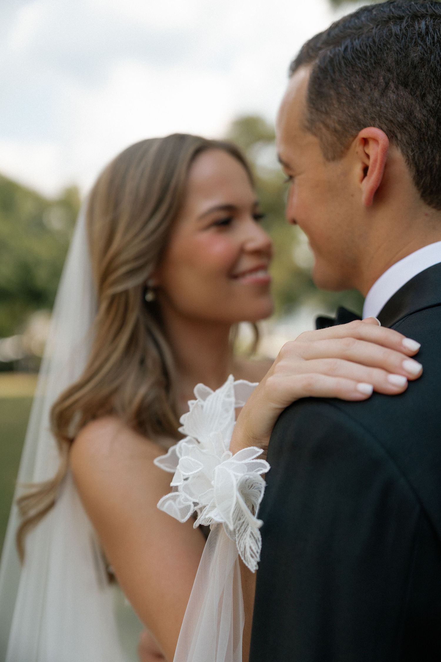 An intimate moment between newlyweds with the bride's hand resting on the groom's shoulder.