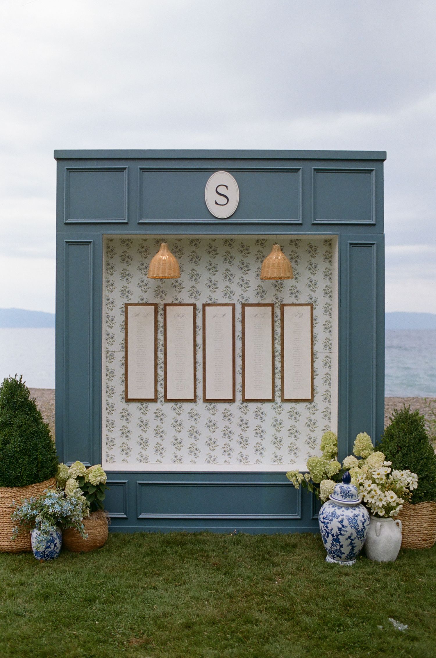 Blue-framed seating chart display with floral accents and decorative wallpaper background.