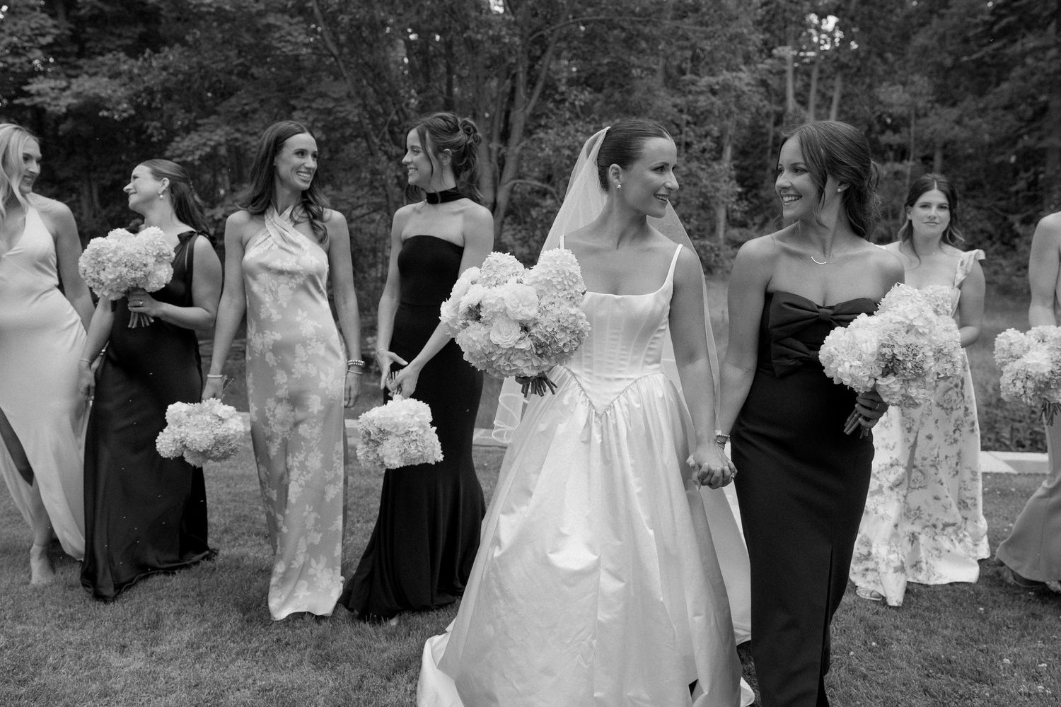 Wedding party celebrates outdoors in black and white photography.