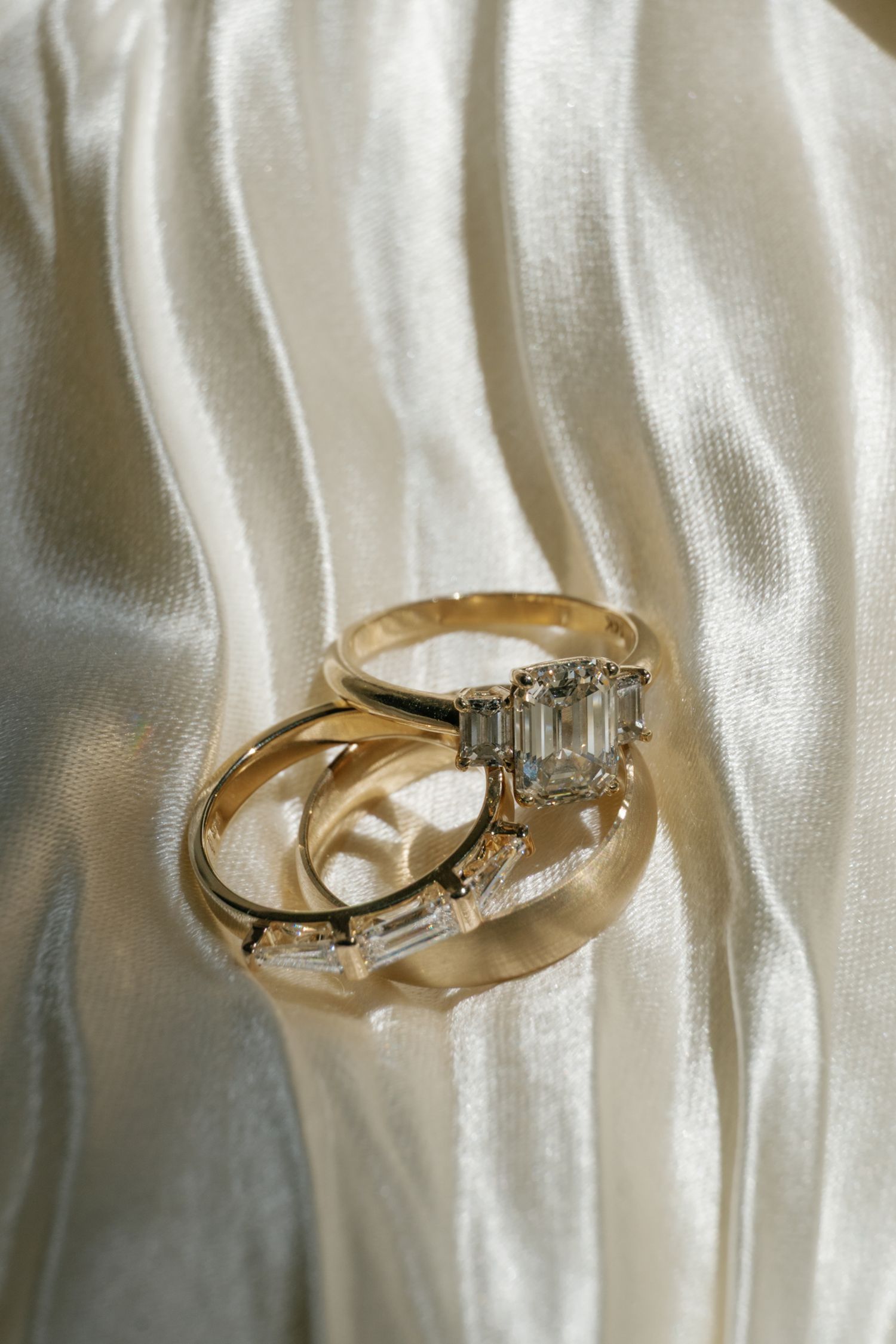 Wedding rings with diamonds displayed on white silk fabric.