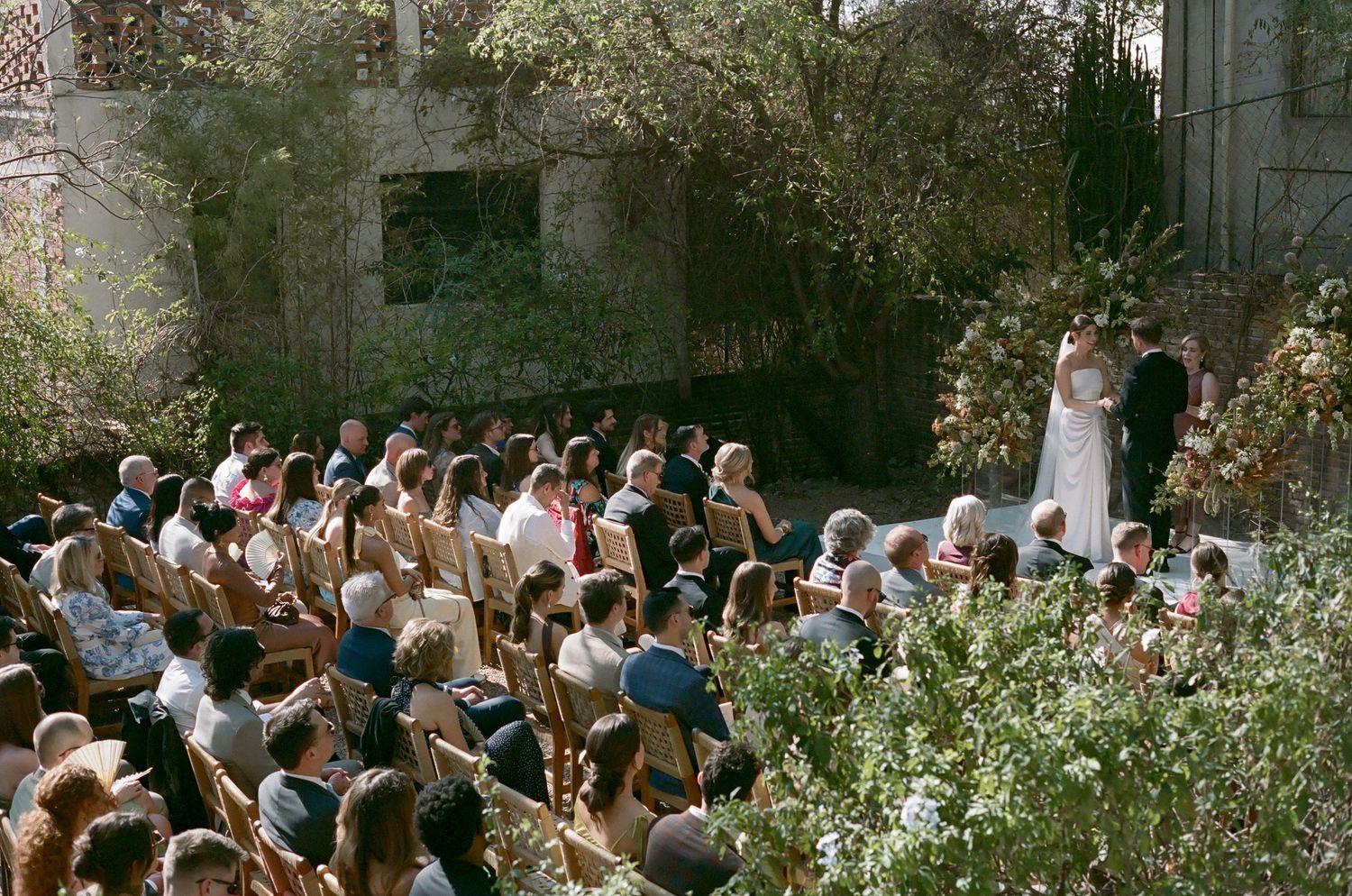 Aerial view of wedding ceremony with guests seated among garden flowers.